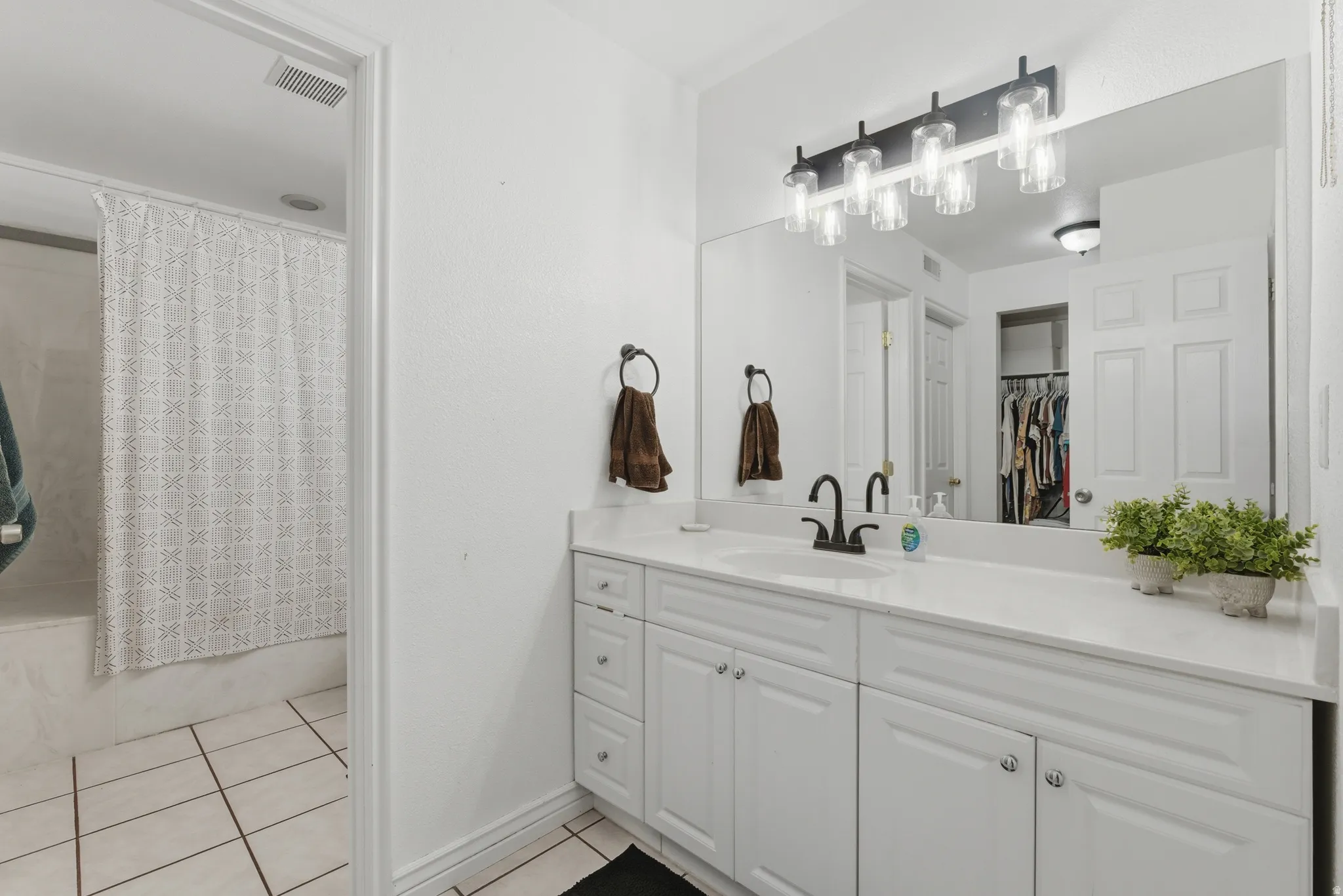 Bathroom featuring vanity, light tile patterned flooring, shower / tub combo with curtain, and a spacious closet