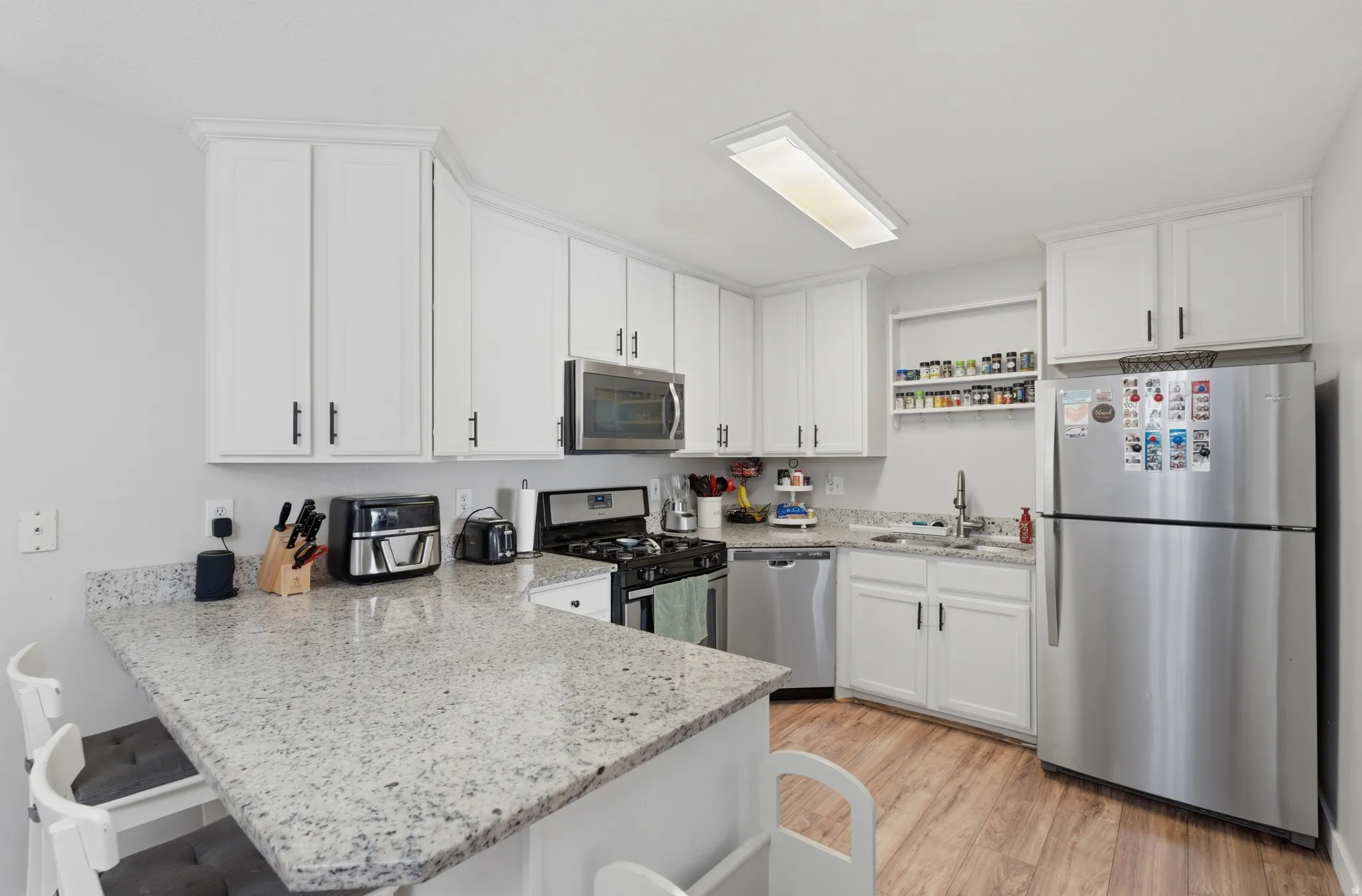 Kitchen featuring stainless steel appliances, white cabinets, and a peninsula