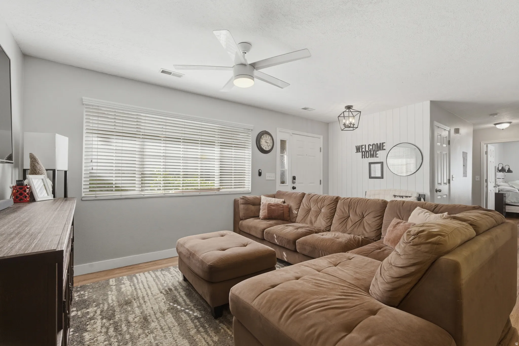 Living room featuring wood finished floors, ceiling fan, and hanging lights