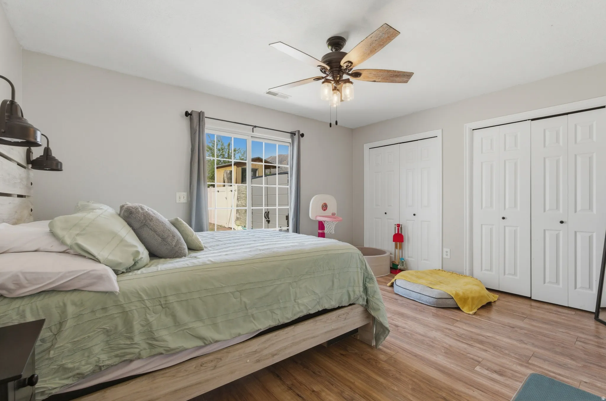 Bedroom featuring two closets, wood finished floors, and a ceiling fan