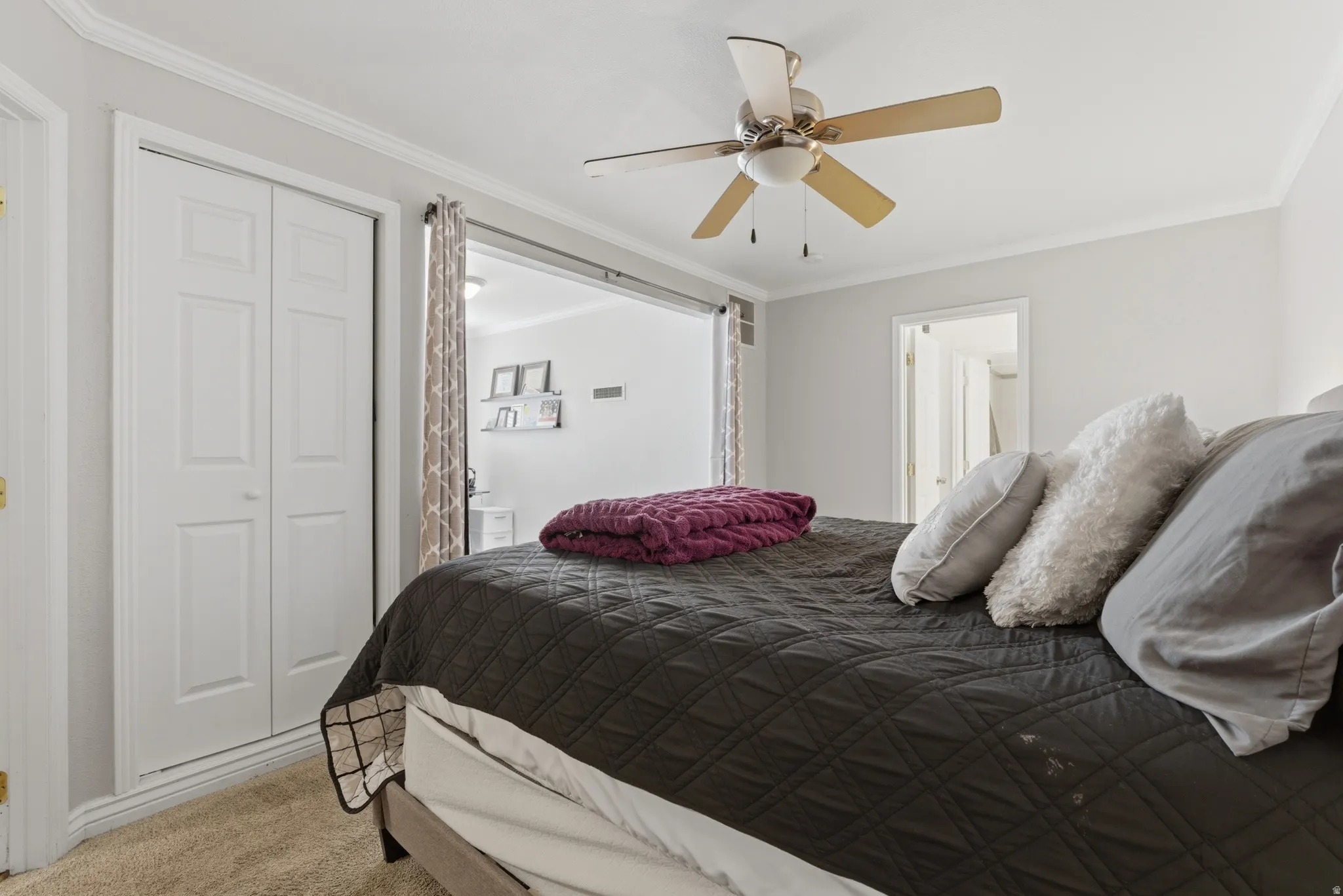 Bedroom featuring crown molding, light carpet, a closet, and a ceiling fan