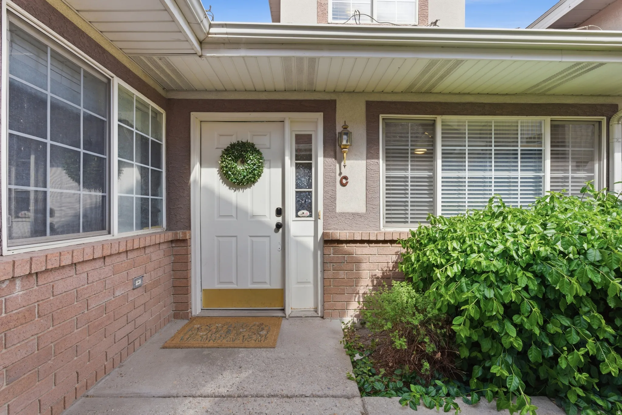 View of exterior entry featuring brick siding and a porch