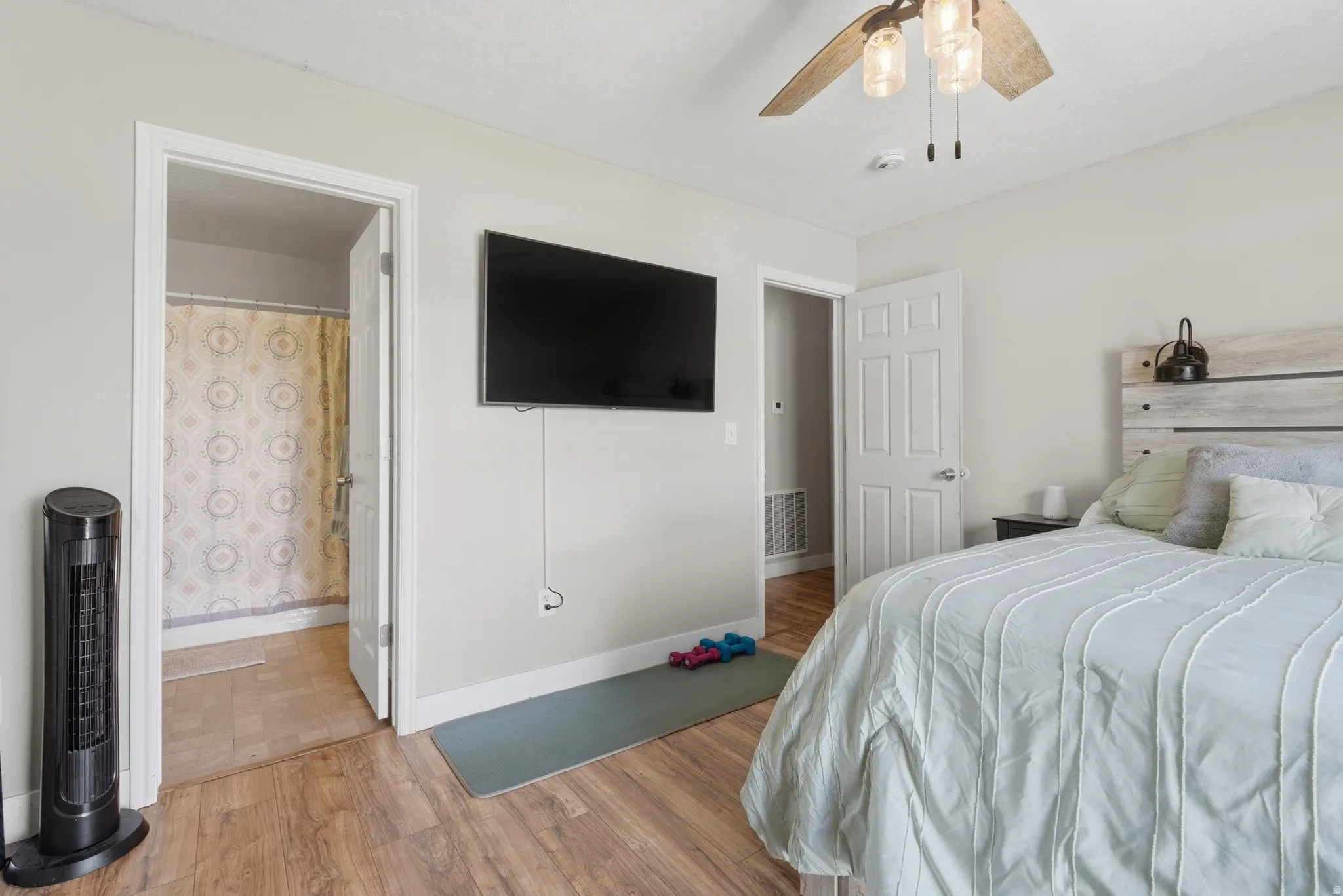 Bedroom featuring light wood-type flooring, ceiling fan, and ensuite bath