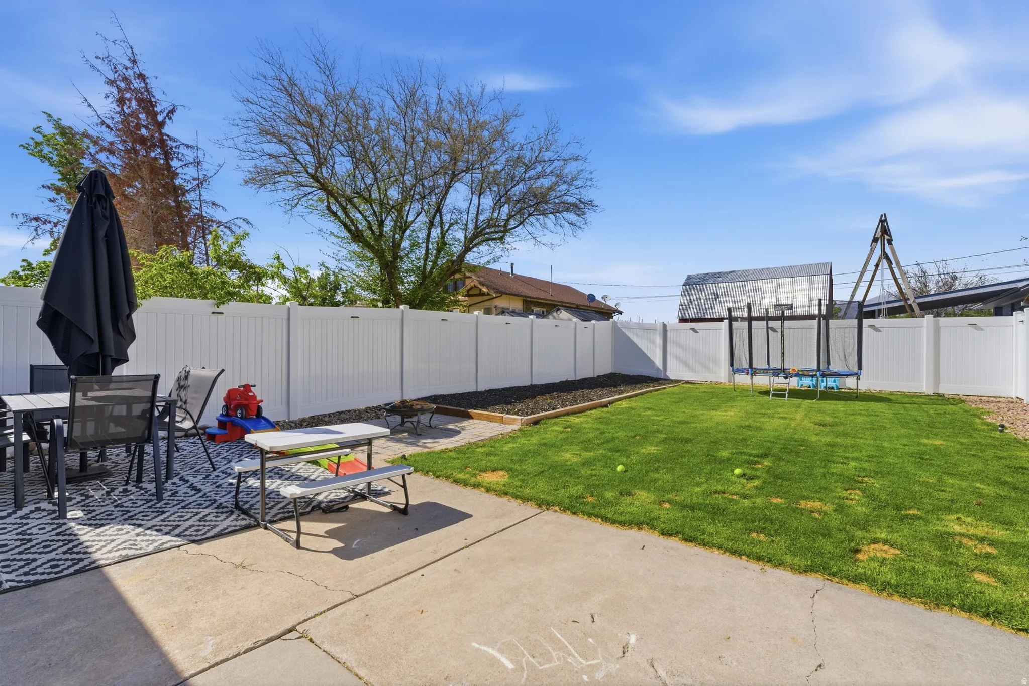 Fenced backyard featuring outdoor dining space, a trampoline, and a patio area