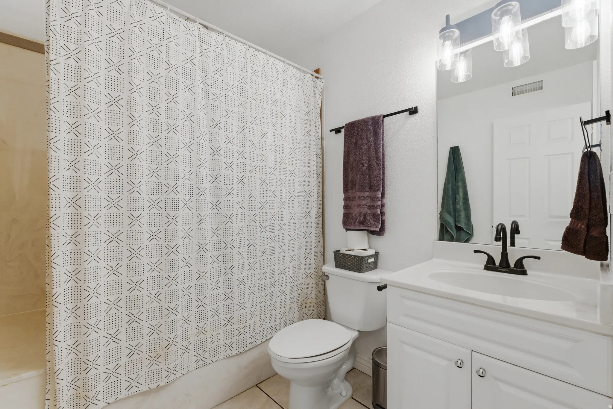 Full bath with vanity, light tile patterned floors, and shower / bath combination with curtain
