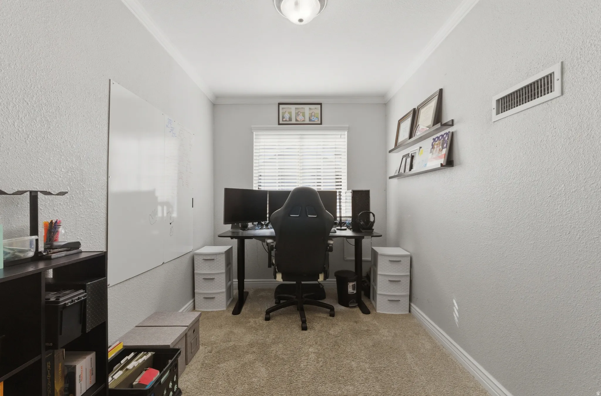 Office with a textured wall, ornamental molding, and light colored carpet