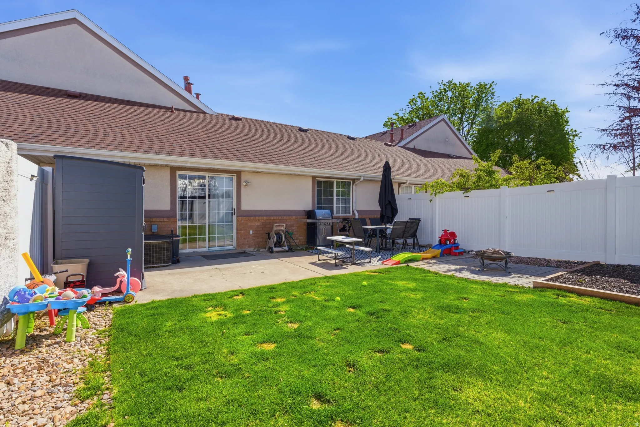 Back of property with a patio area, a fenced backyard, brick siding, roof with shingles, and a fire pit
