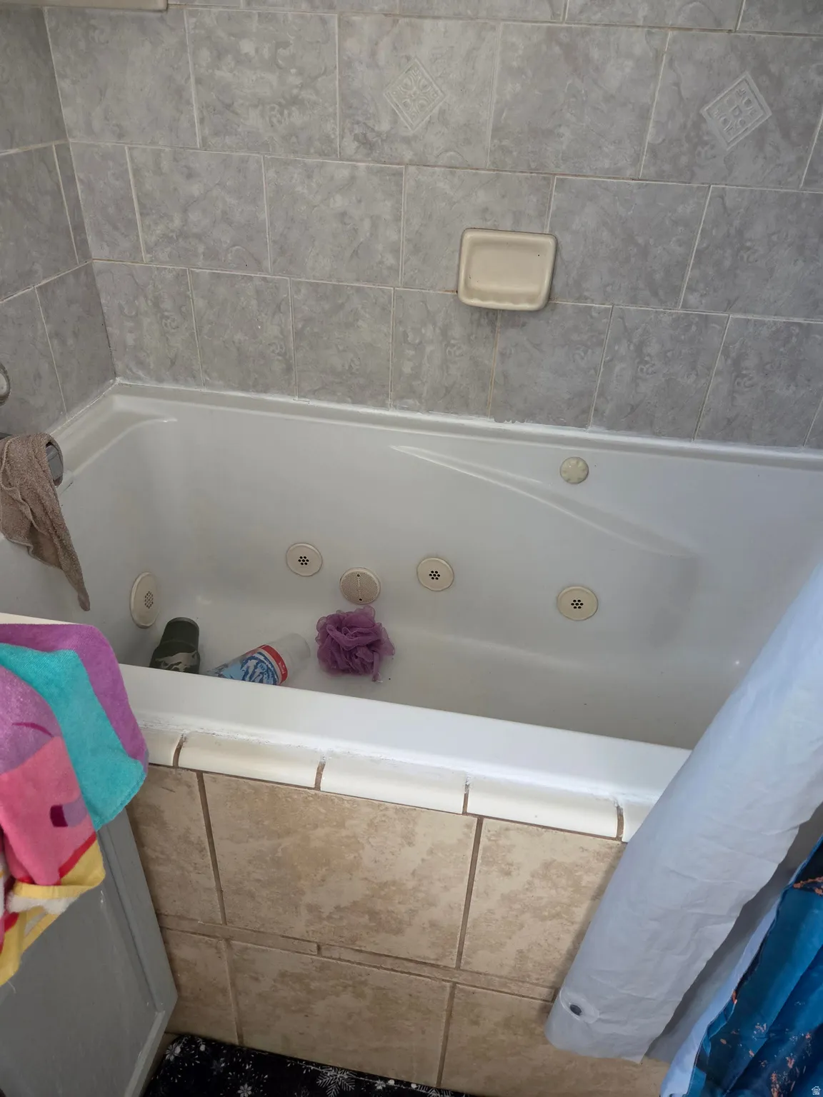 Jetted soaking tub with light gray wall tiling and decorative accent tiles