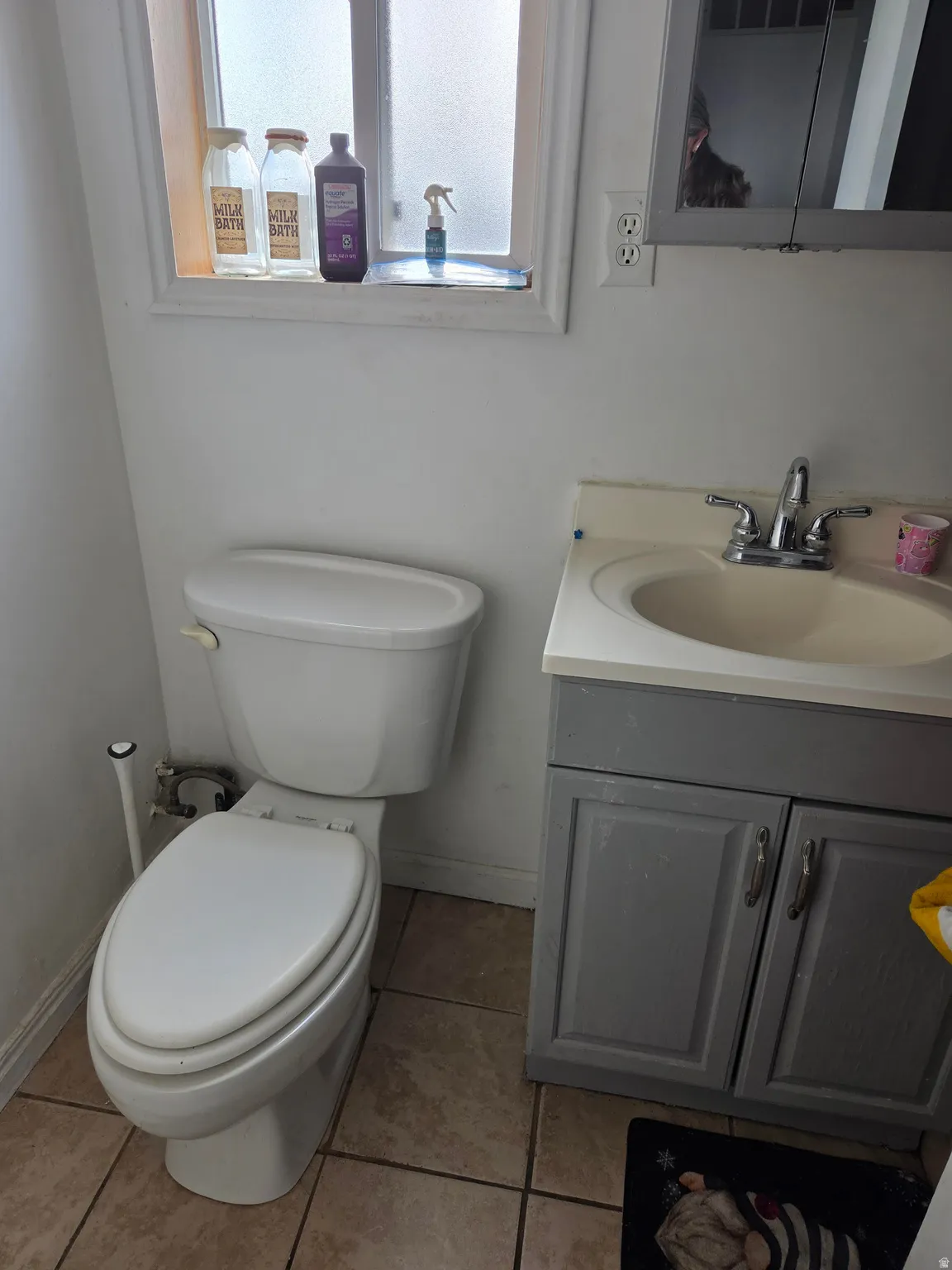 Single vanity with a white countertop and integrated sink, chrome faucet, and gray cabinet storage