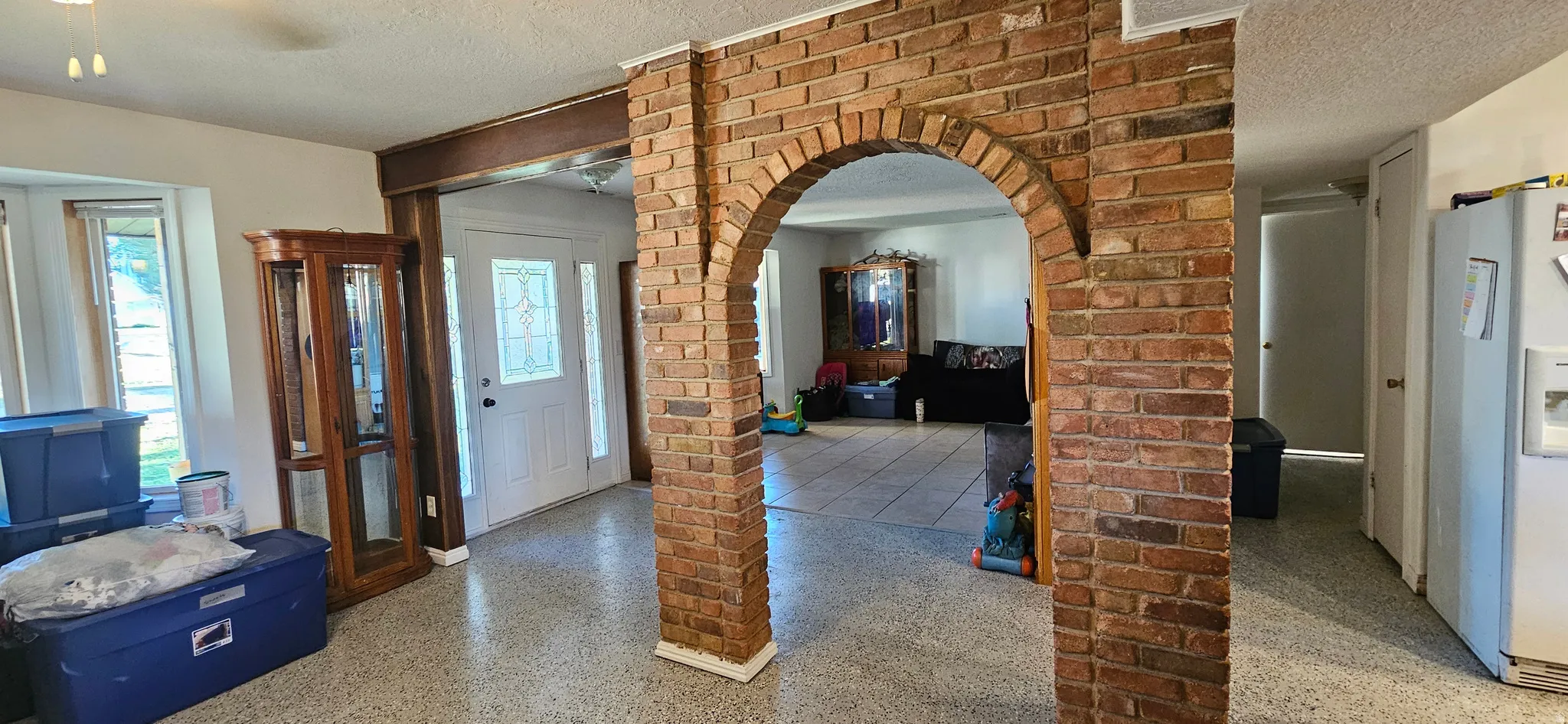 Entrance foyer with a textured ceiling, arched walkways, and speckled floor