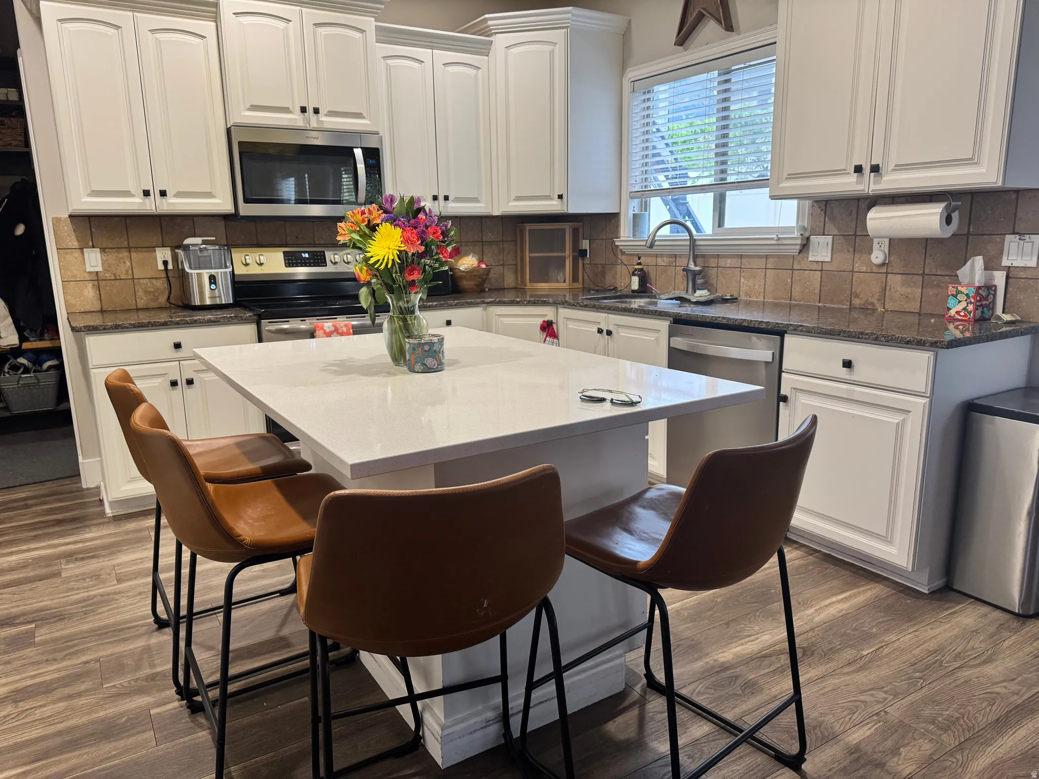 Kitchen with white cabinetry, dark stone counters, tasteful backsplash, a center island, and a kitchen breakfast bar