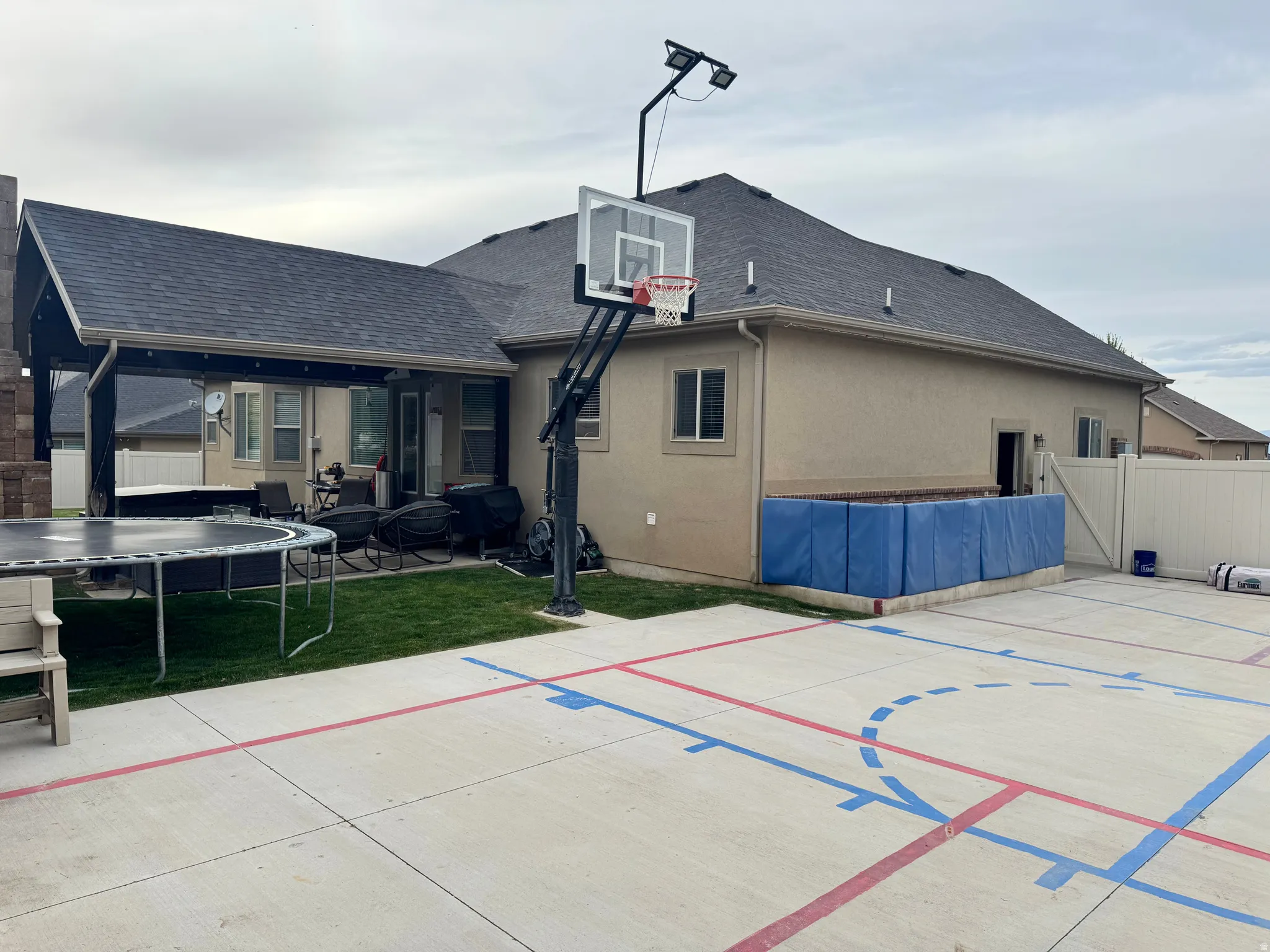 View of basketball court featuring a trampoline, a patio, and basketball court