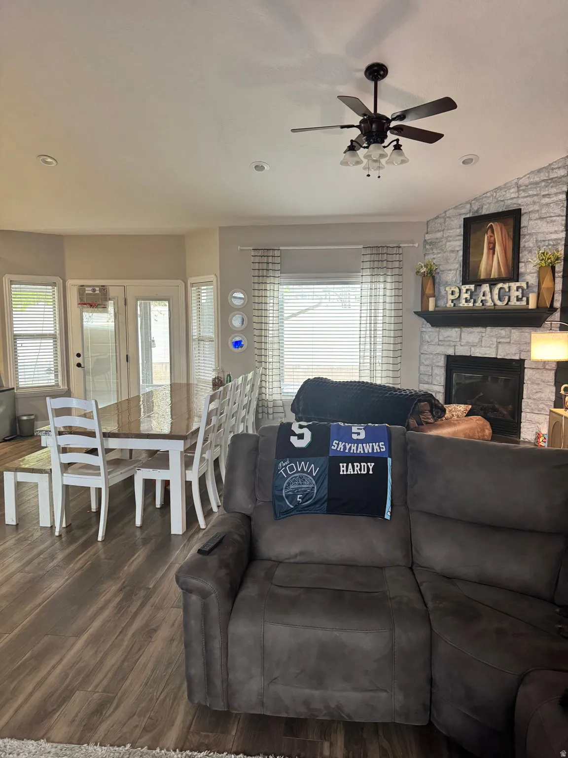 Living area with dark wood-style floors, ceiling fan, a fireplace, lofted ceiling, and plenty of natural light