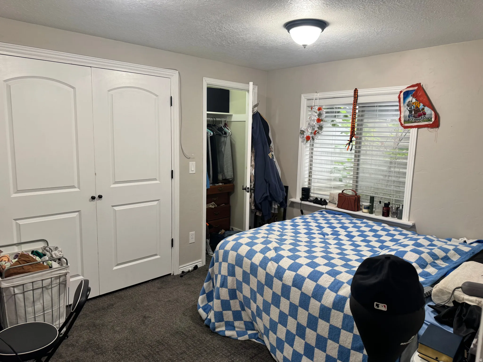 Bedroom with a closet, dark carpet, and a textured ceiling