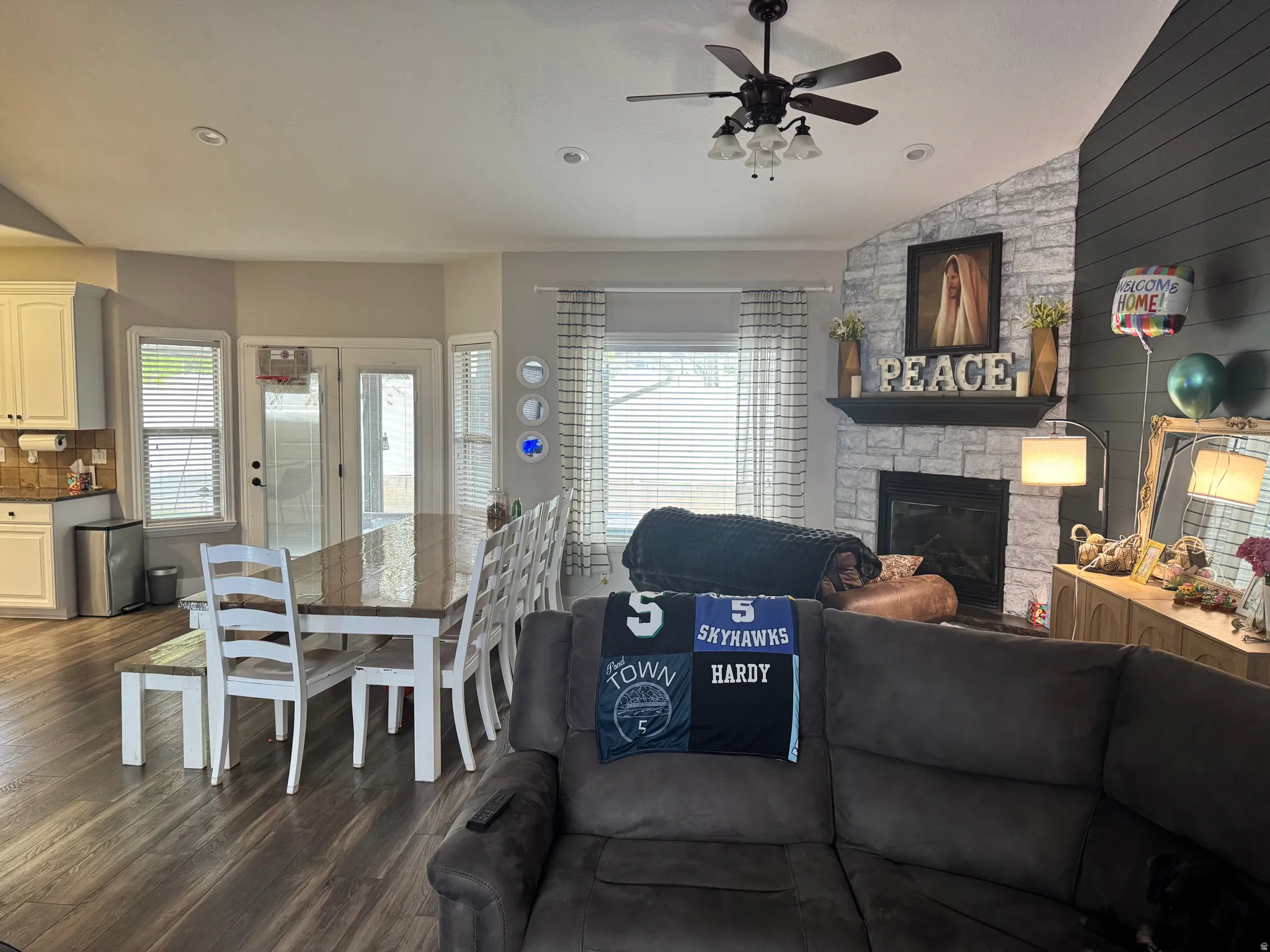 Living area with dark wood finished floors, a fireplace, lofted ceiling, ceiling fan, and recessed lighting