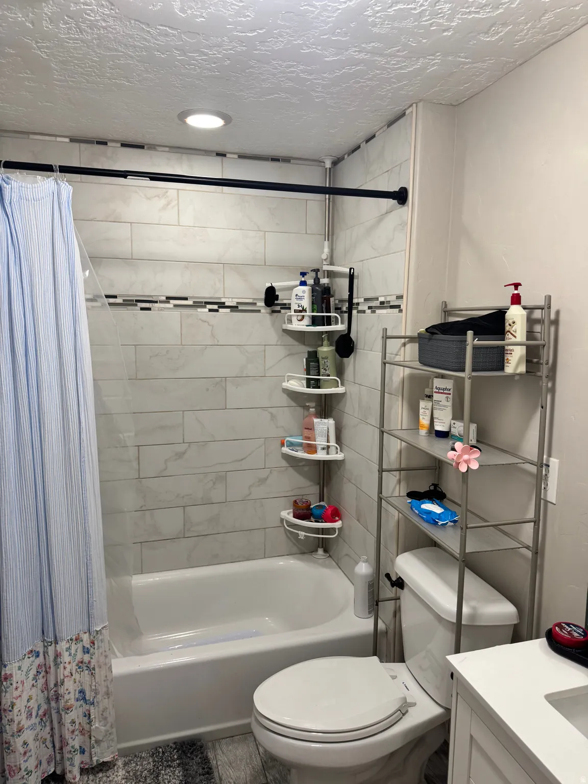 Full bath with shower / tub combo, vanity, and a textured ceiling