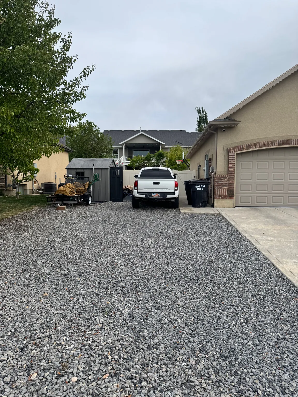 View of parking with a storage unit and concrete driveway