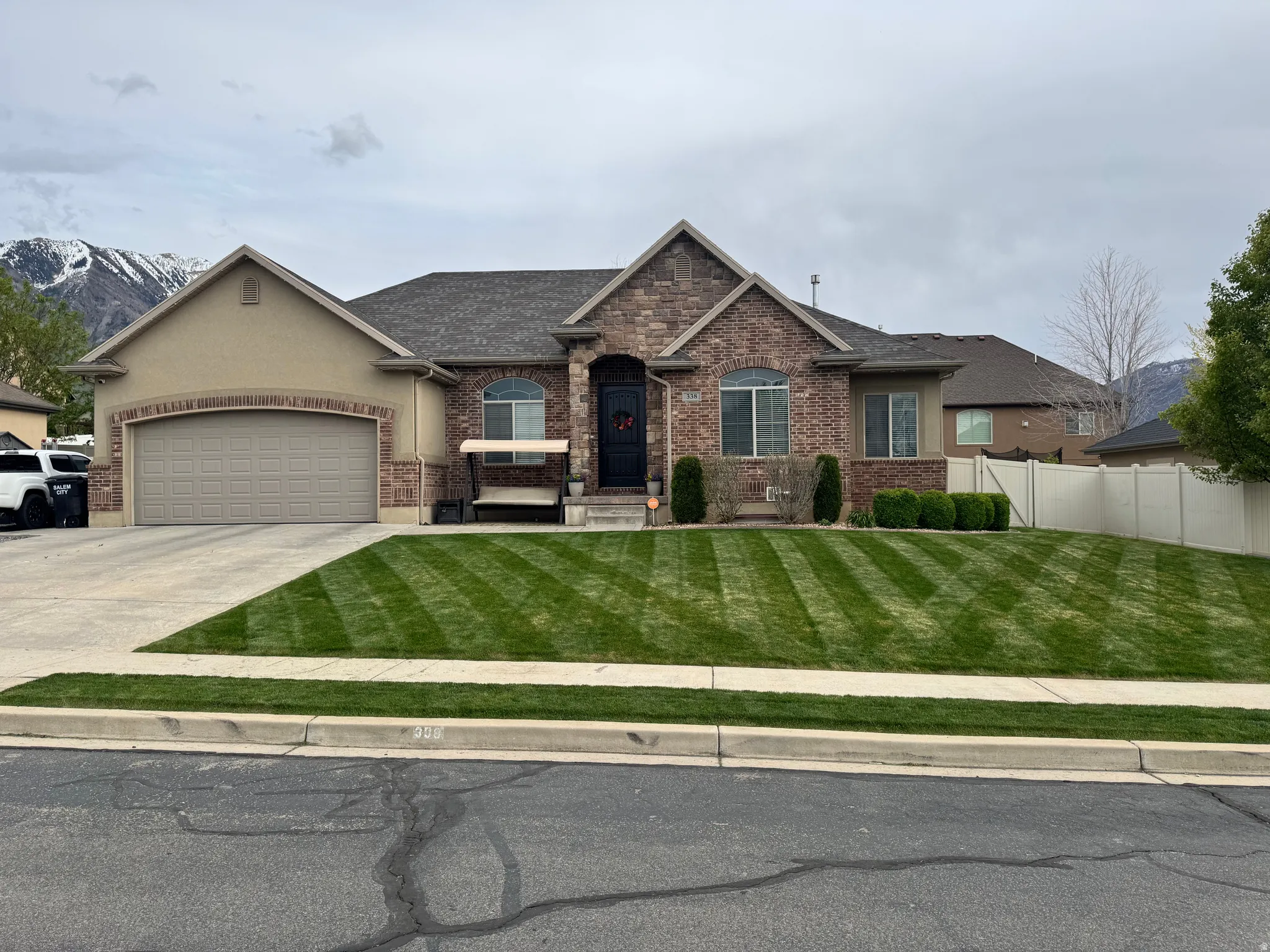 View of front of property featuring a garage, concrete driveway, brick siding, a mountain view, and roof with shingles