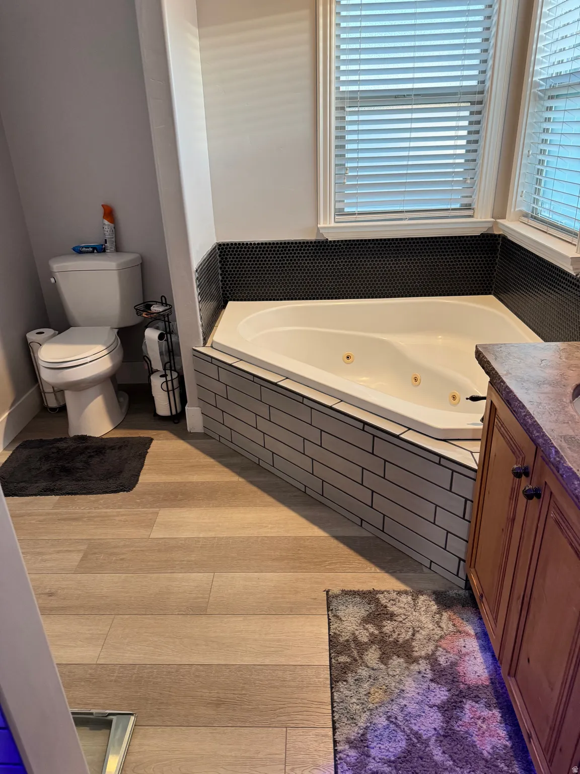 Corner jetted tub with black penny tile surround and subway tile base