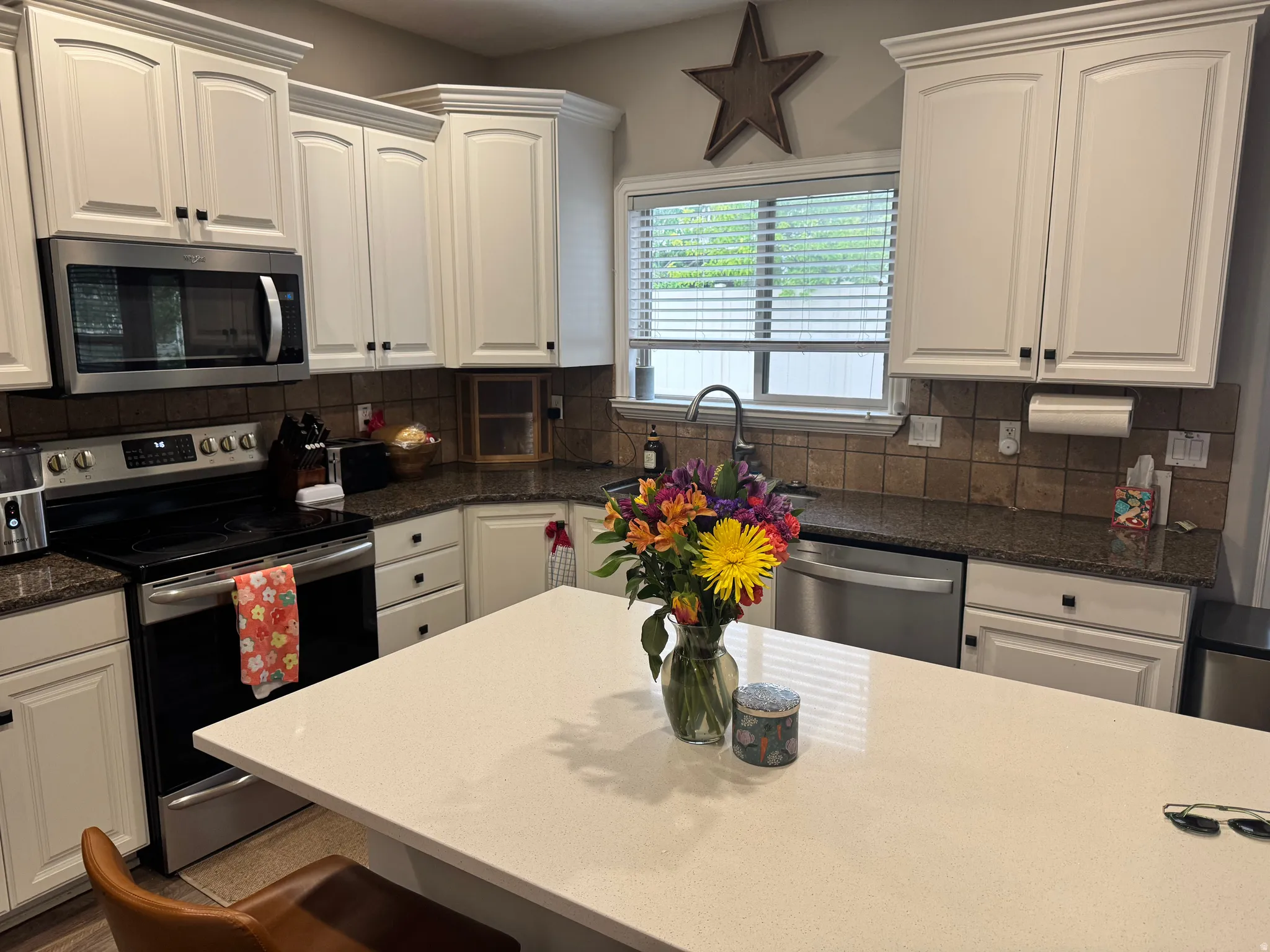 Kitchen with stainless steel appliances, white cabinets, dark stone countertops, and decorative backsplash