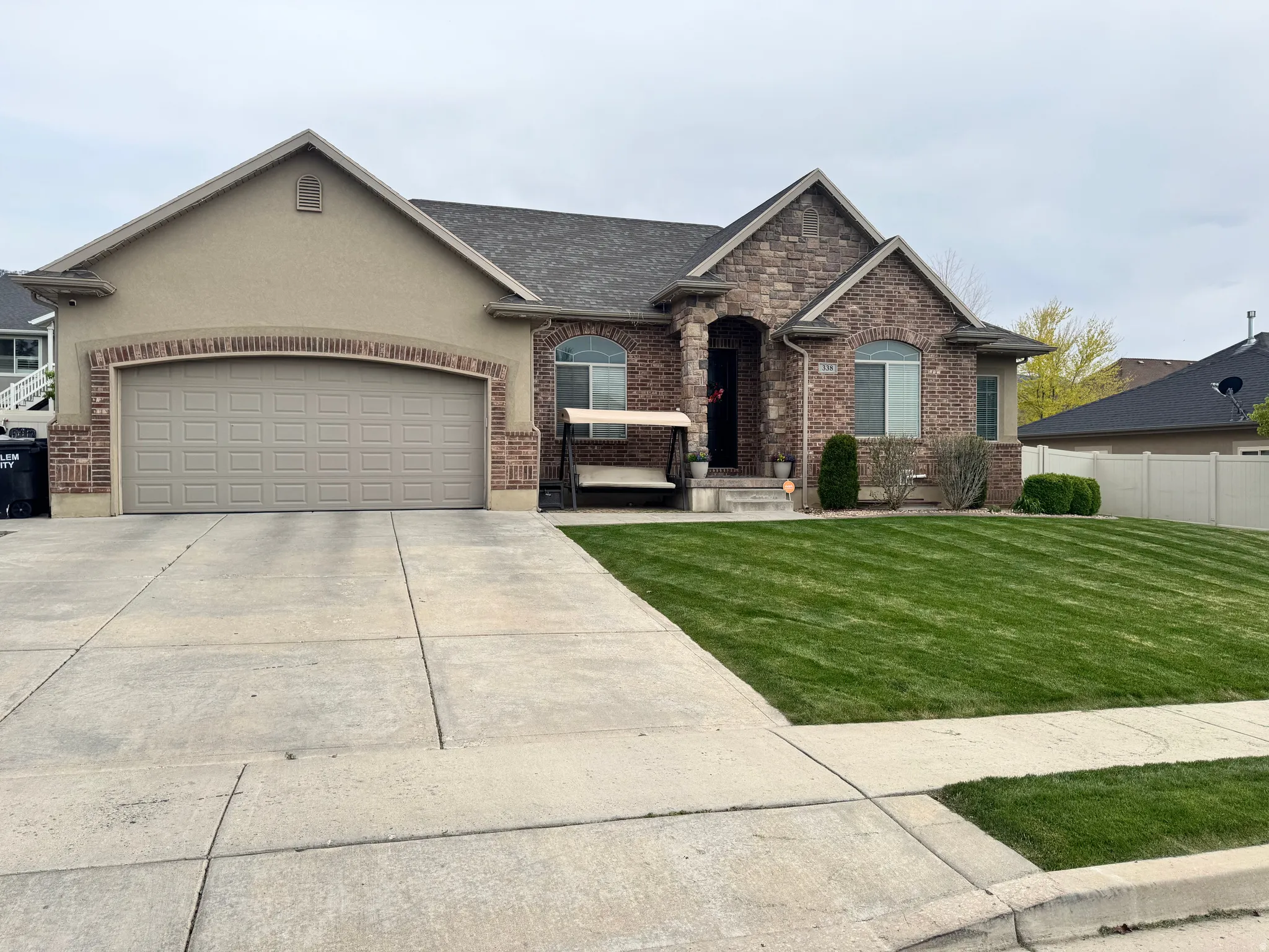 View of front of home with a garage, concrete driveway, brick siding, and roof with shingles