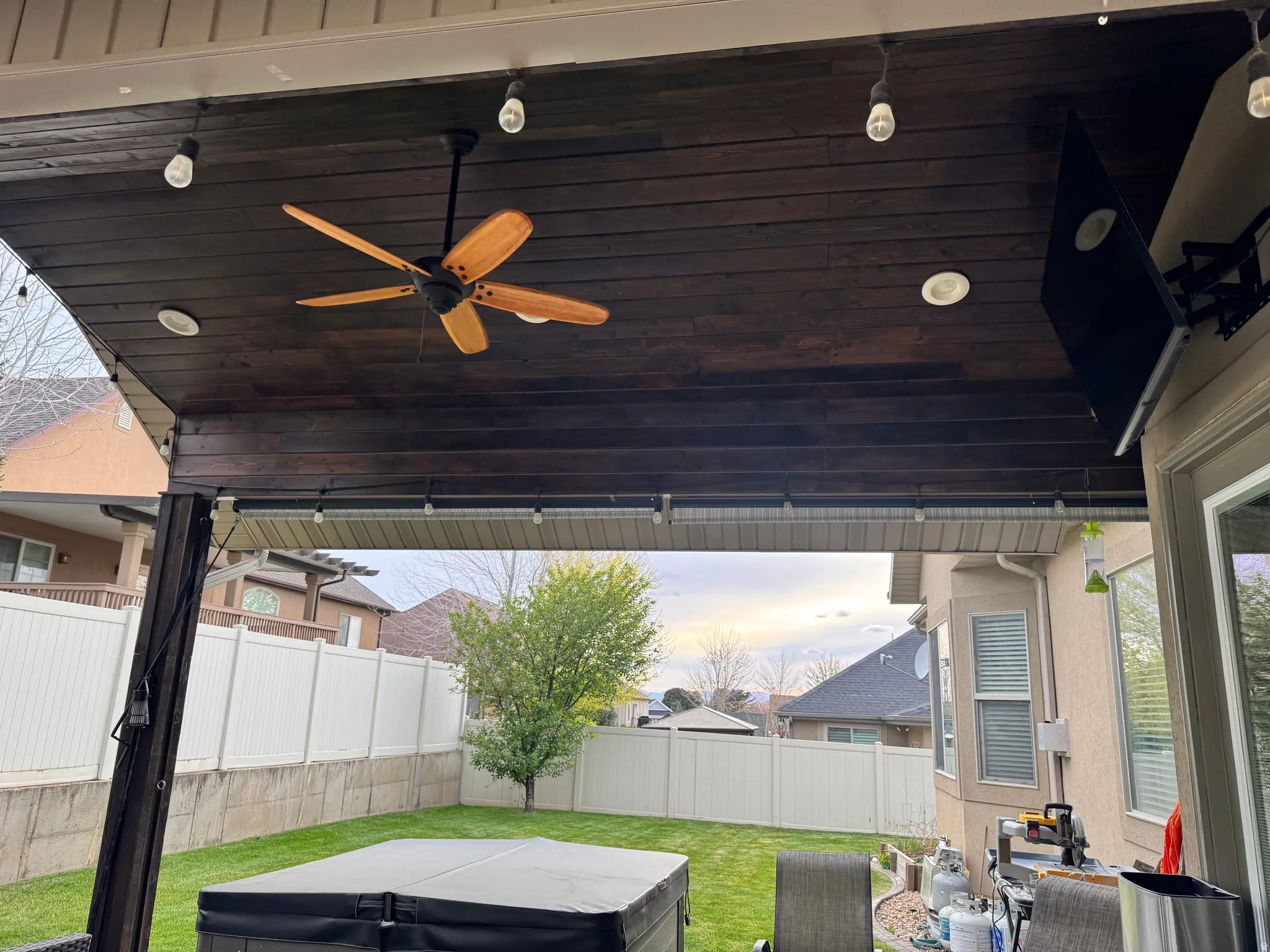 Patio terrace at dusk featuring ceiling fan, a fenced backyard, and a patio area