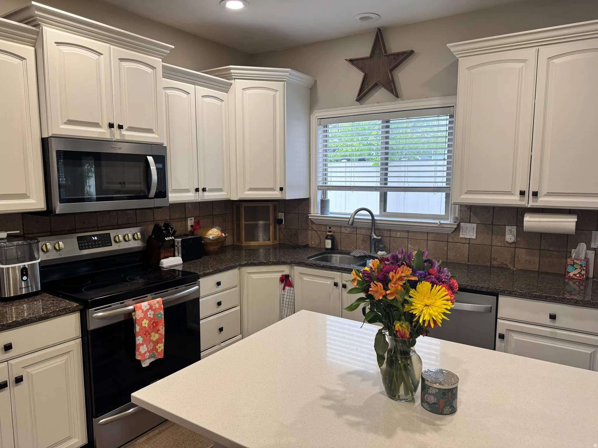 Kitchen featuring stainless steel appliances, dark stone counters, white cabinetry, recessed lighting, and tasteful backsplash