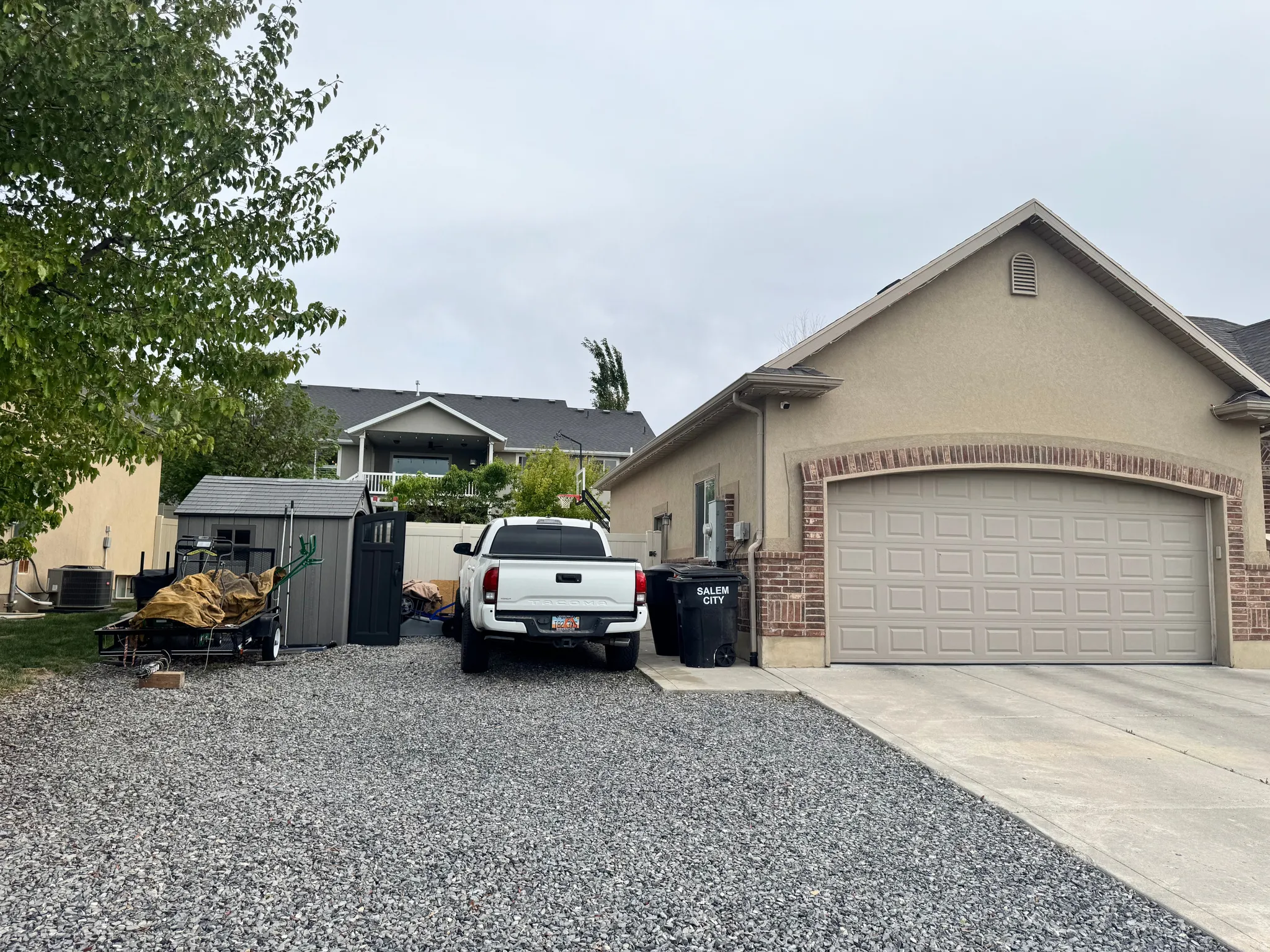 View of front of property featuring driveway, brick siding, stucco siding, and an attached garage