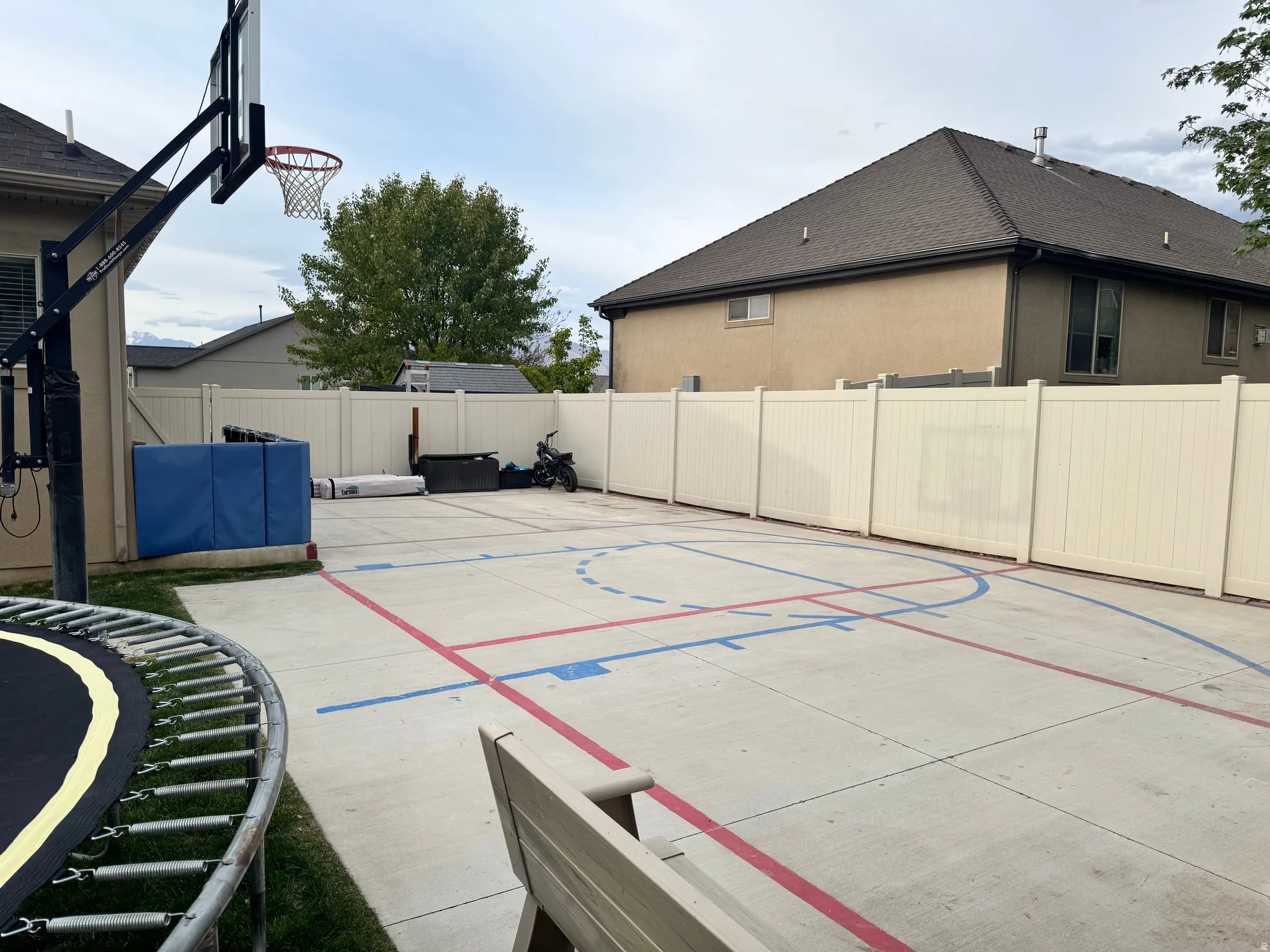 View of sport court with a fenced backyard and a trampoline