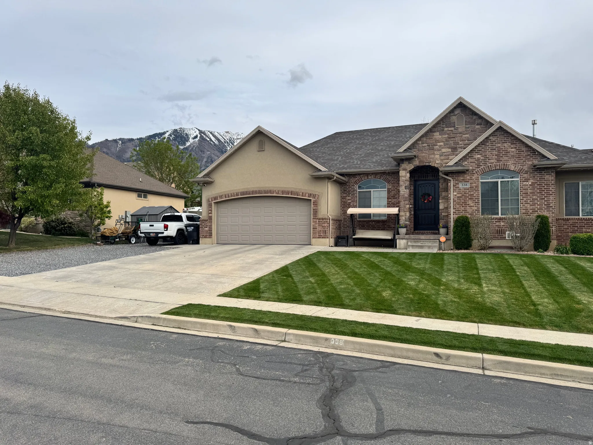 View of front of home featuring an attached garage, concrete driveway, a front lawn, and a shingled roof