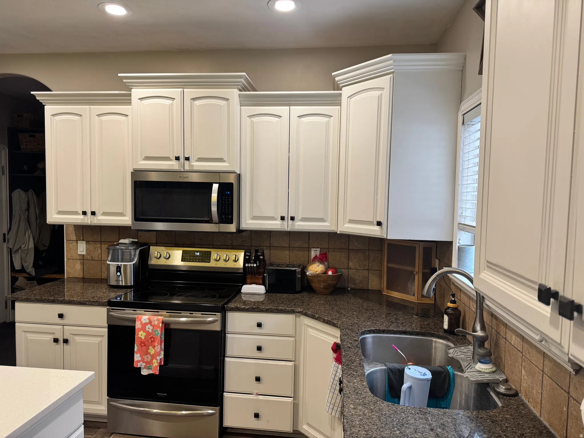 Kitchen featuring stainless steel appliances, tasteful backsplash, white cabinets, and recessed lighting