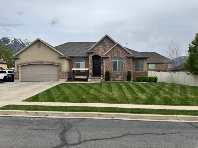 View of front of property featuring a garage, concrete driveway, brick siding, a mountain view, and roof with shingles