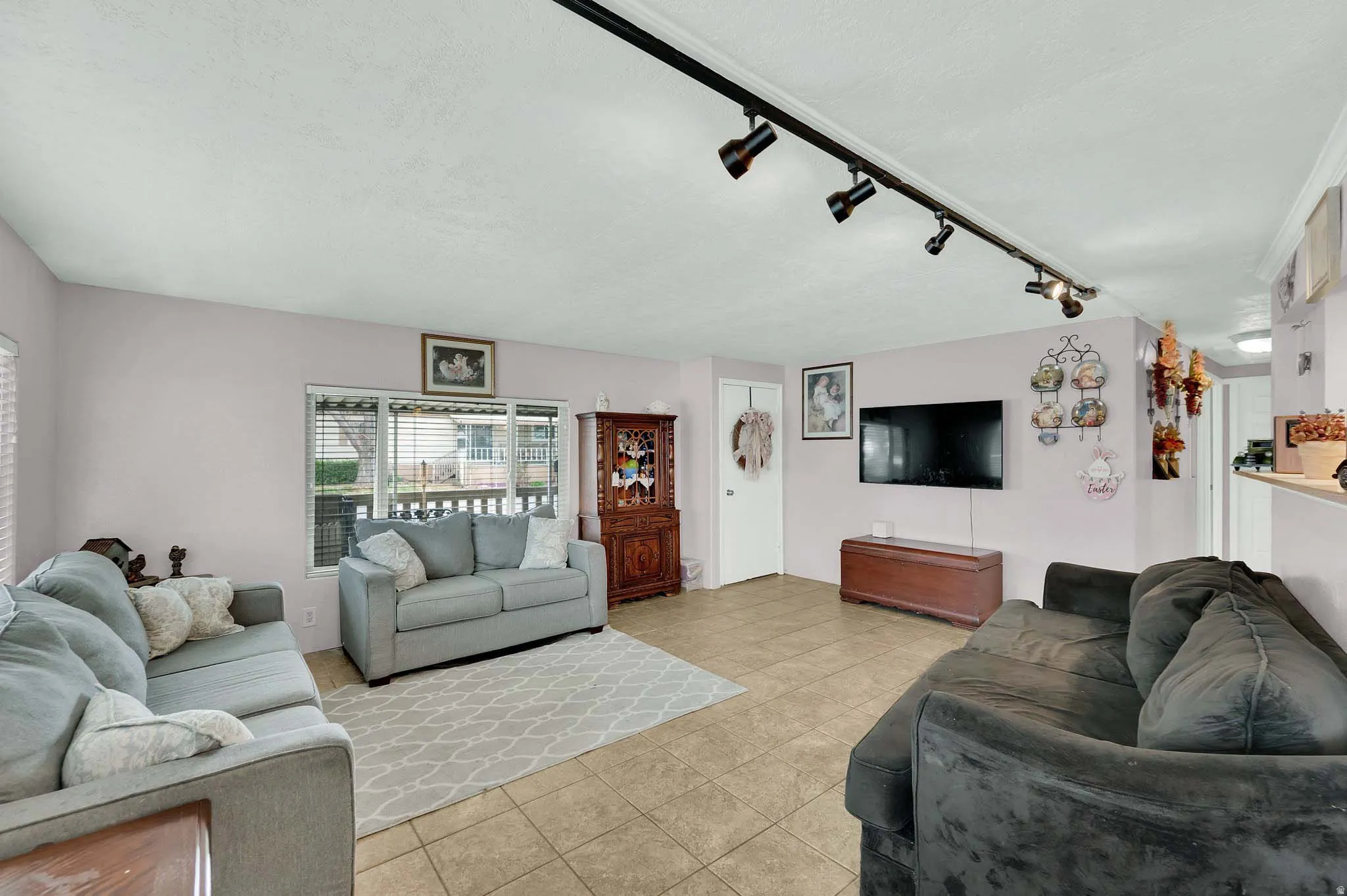 Living room featuring rail lighting and light tile patterned floors