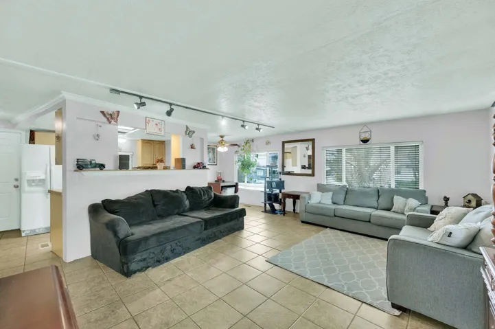 Living area featuring track lighting, light tile patterned flooring, a textured ceiling, and ceiling fan