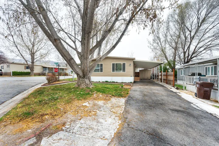 Manufactured / mobile home featuring a carport and asphalt driveway