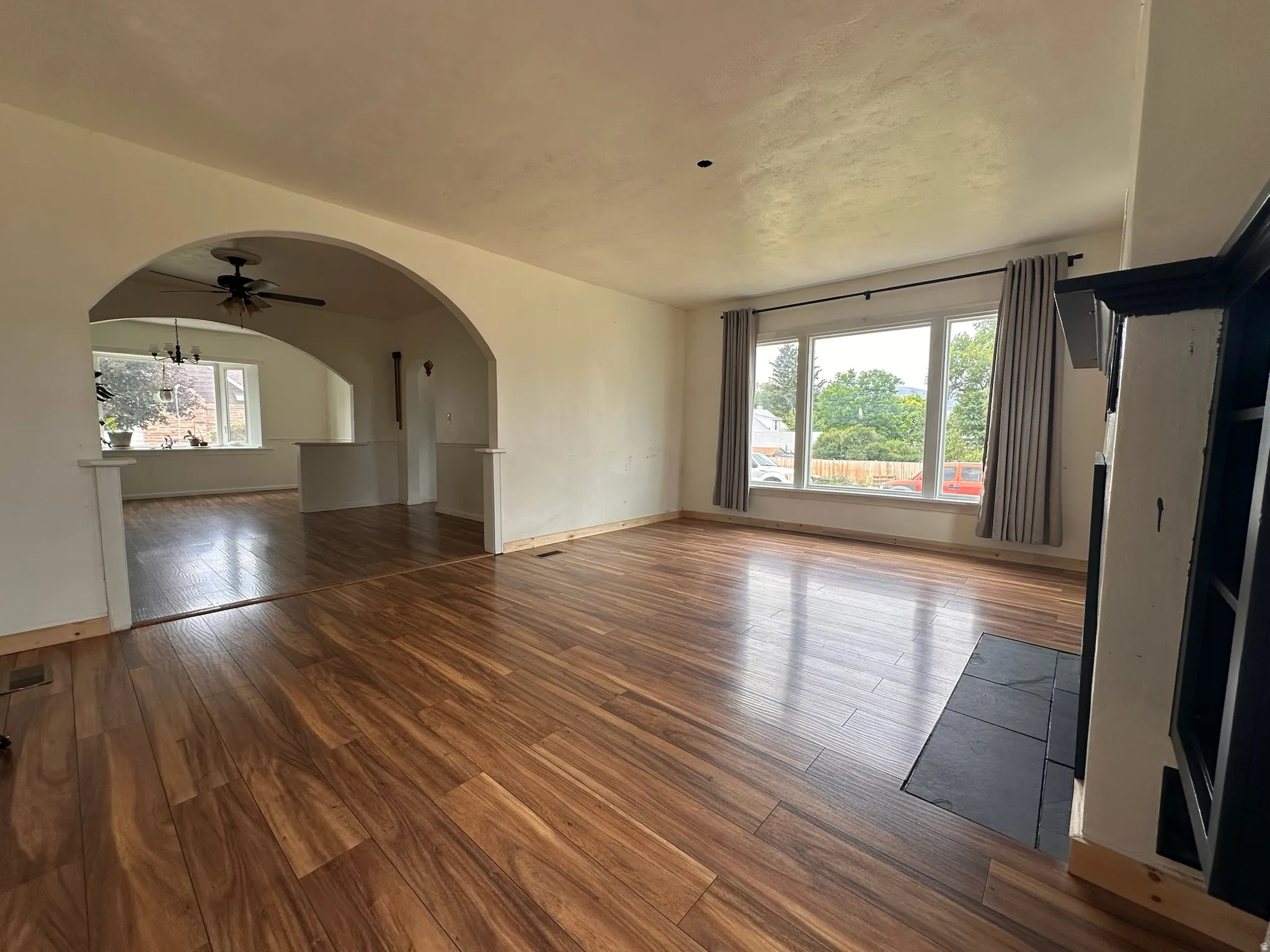 Spacious interior featuring wood-finish flooring, a prominent arched doorway, and a fireplace with a dark-tiled hearth and built-in shelving