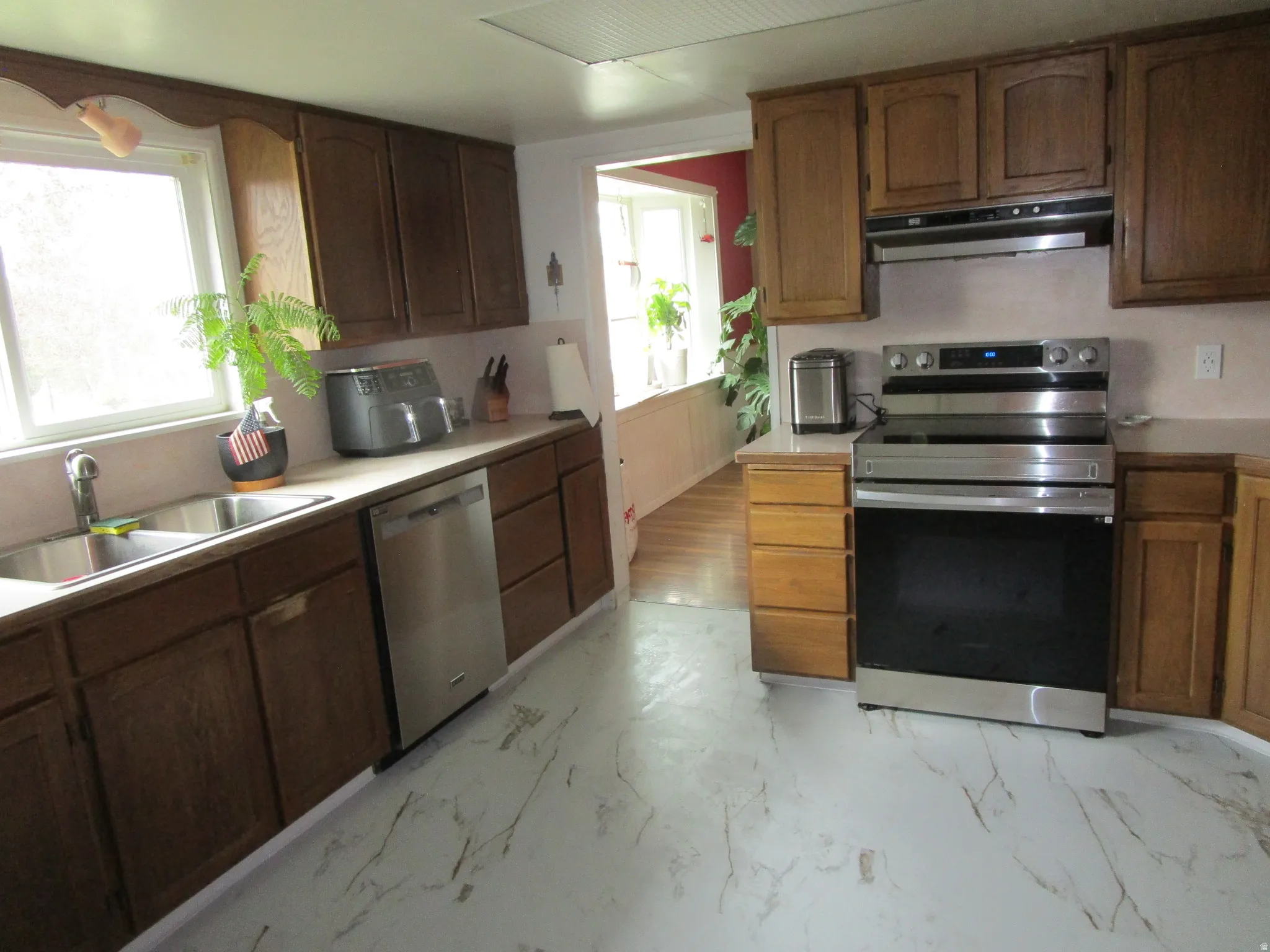 Kitchen featuring stainless steel appliances, light countertops, and light marble finish flooring