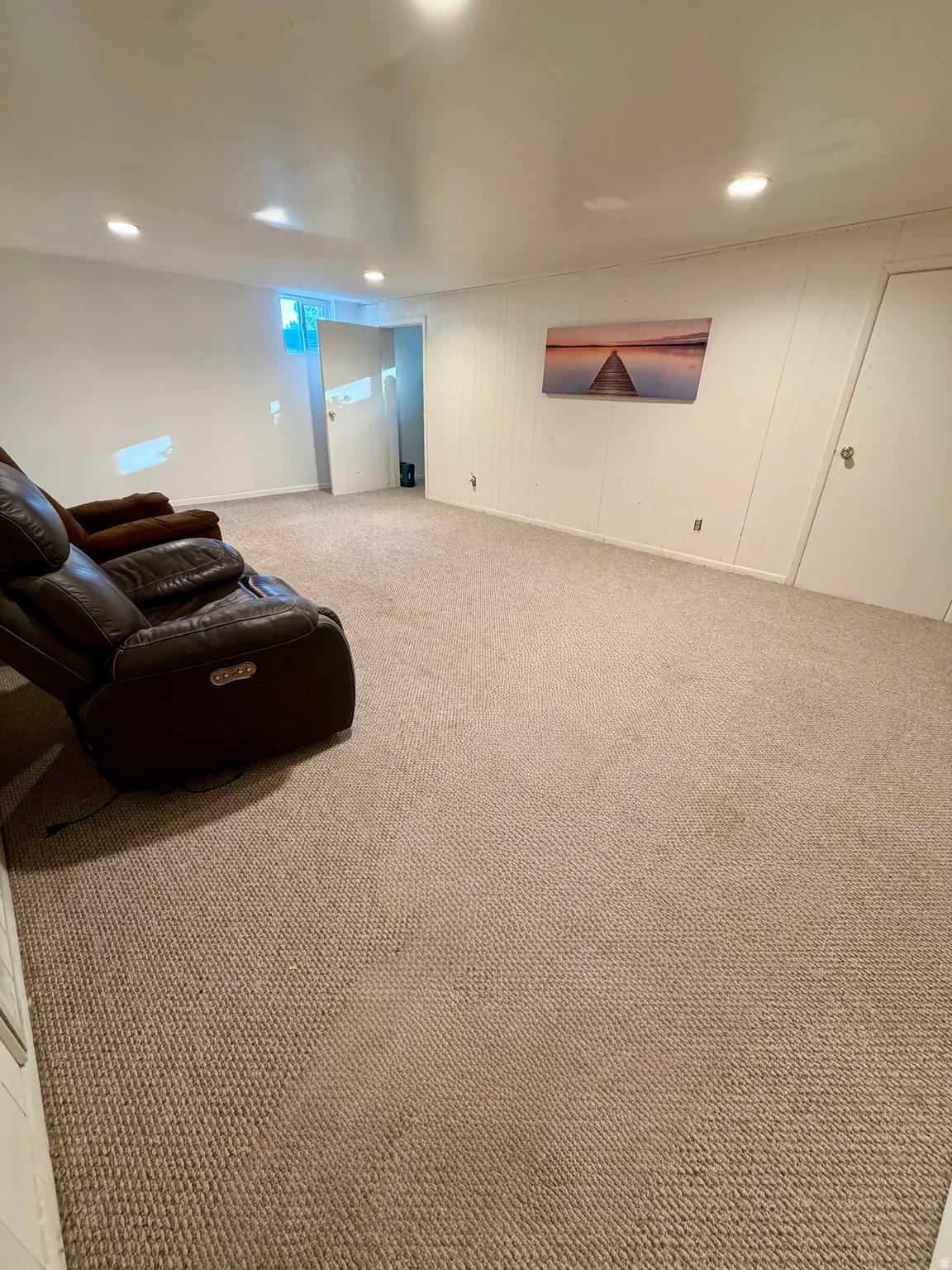 Spacious room featuring neutral carpeting, recessed lighting, and white paneled walls