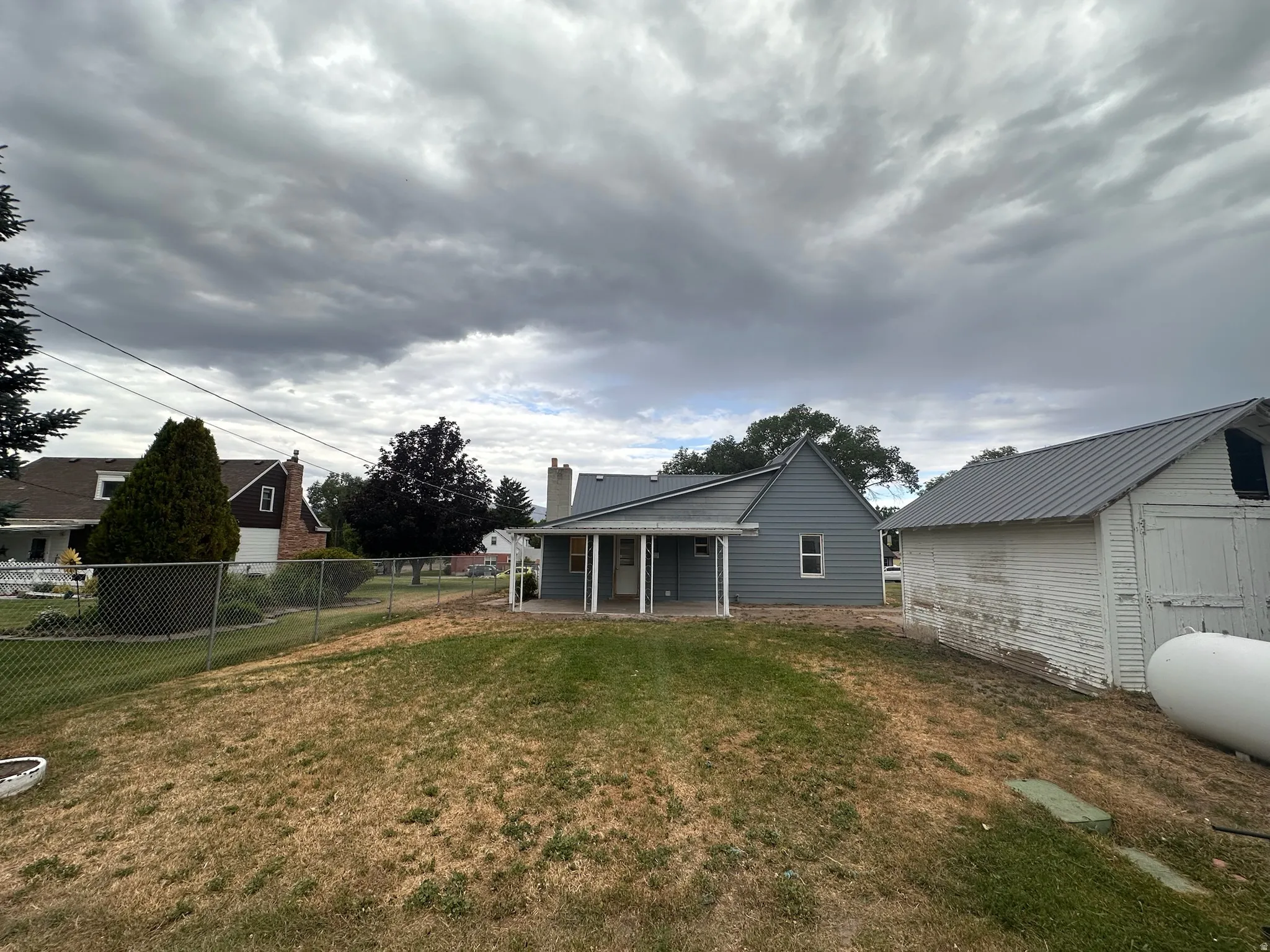 Rear elevation featuring light blue siding, a covered patio, and a metal roof