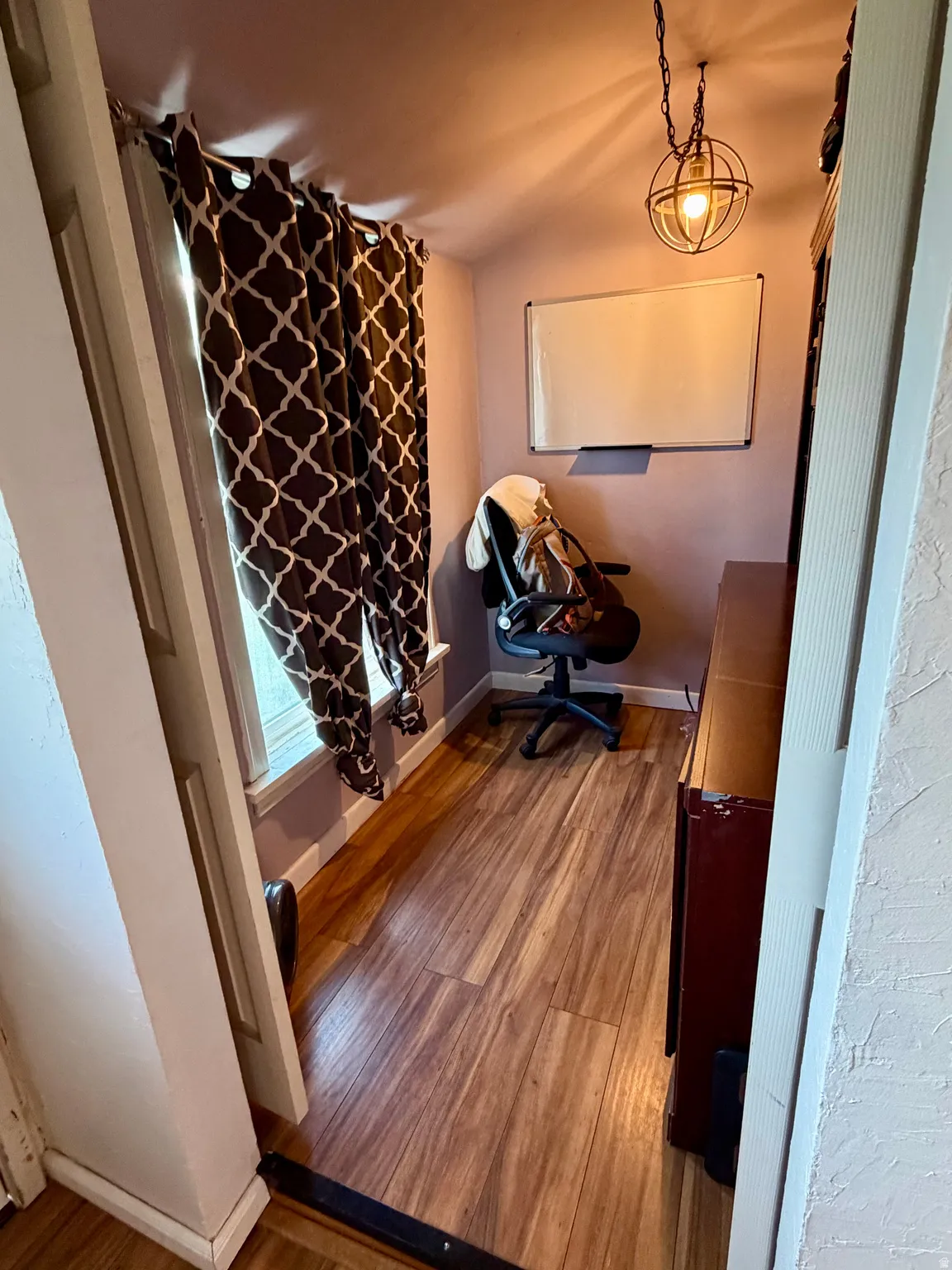 Compact interior space featuring wood-finish flooring, a window with trim, baseboards, and a contemporary spherical pendant light fixture