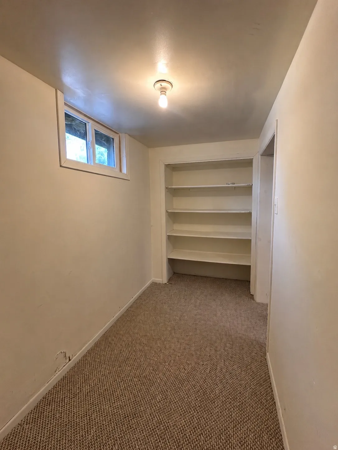 Room with recessed window, integrated shelving, and wall-mounted light fixture