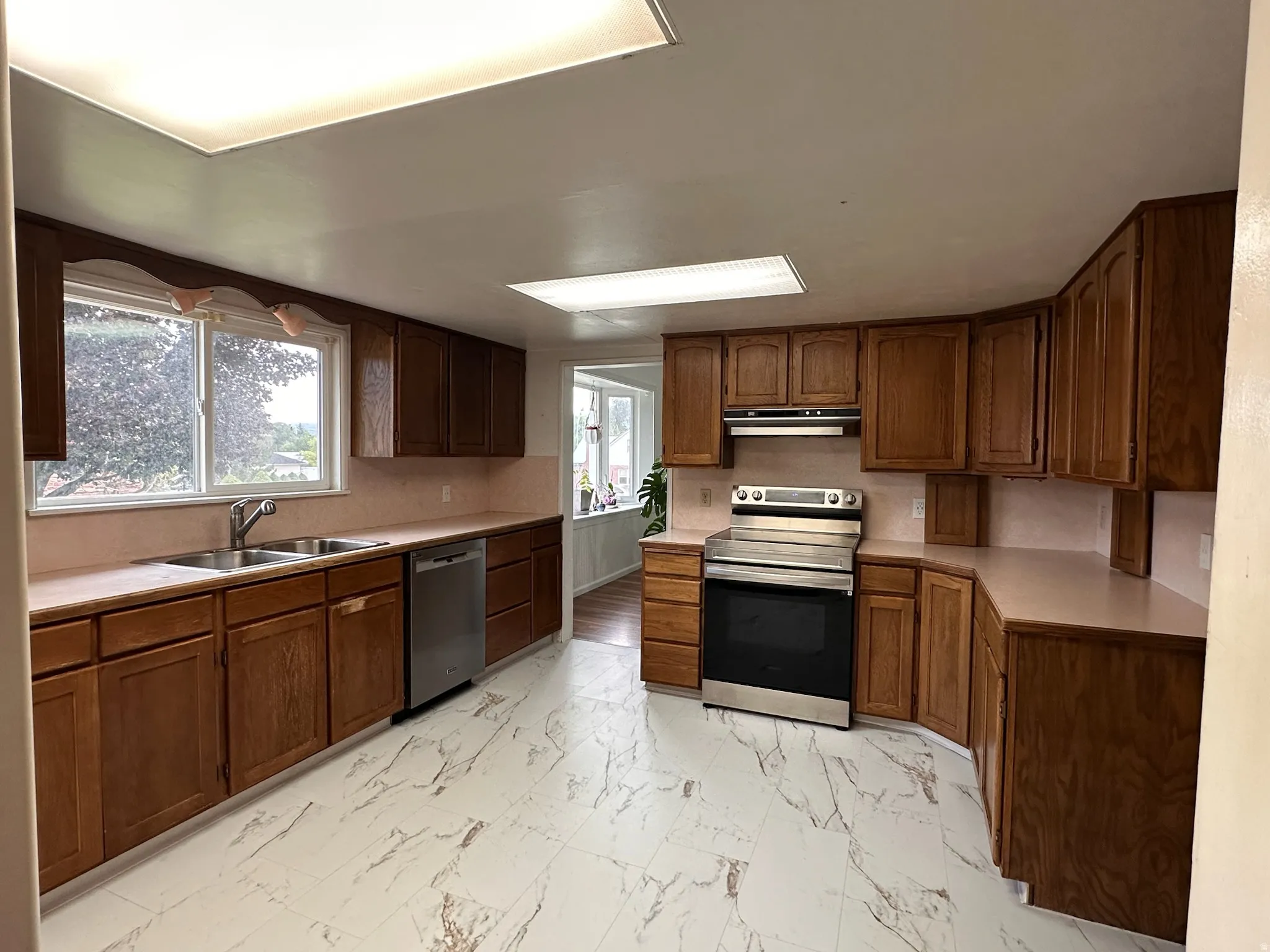 Kitchen featuring wood-finish cabinetry, stainless steel appliances, and a dual basin sink