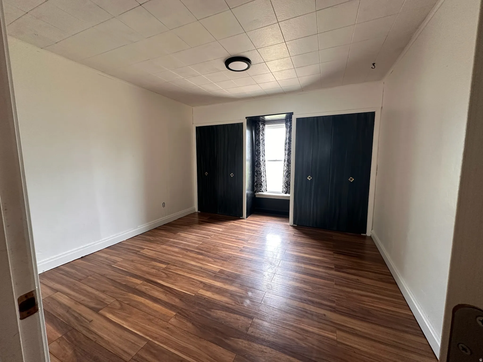 Room featuring wood-finish flooring, white baseboards, and neutral wall paint