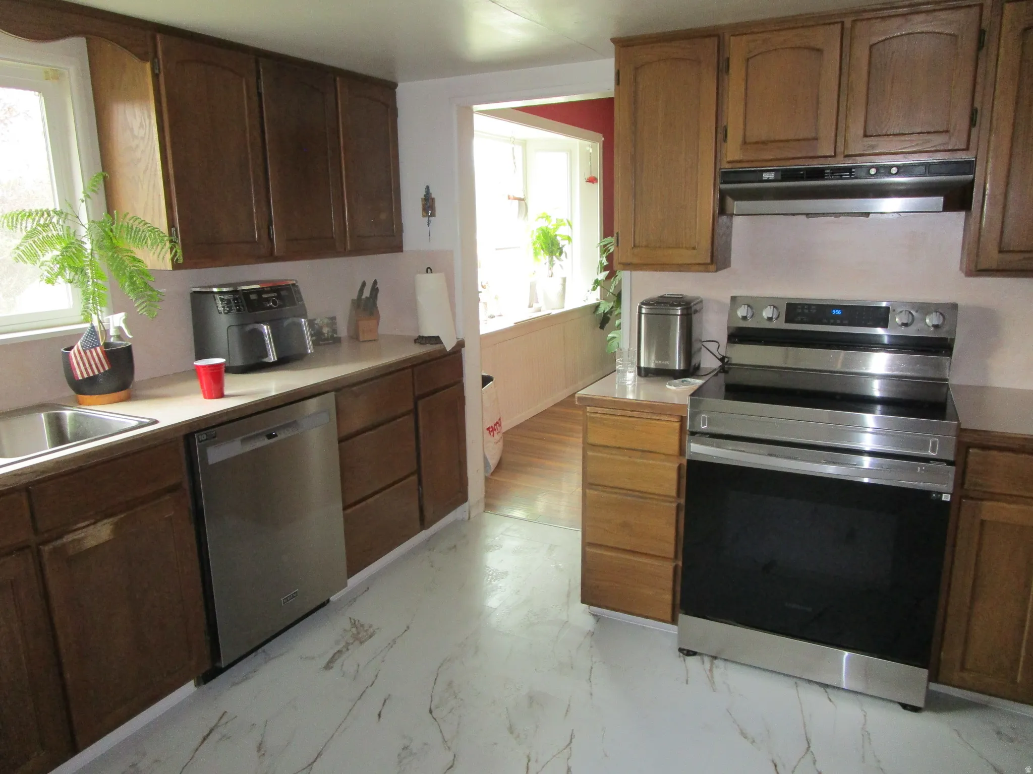 Kitchen with stainless steel appliances, light countertops, and light marble finish floors