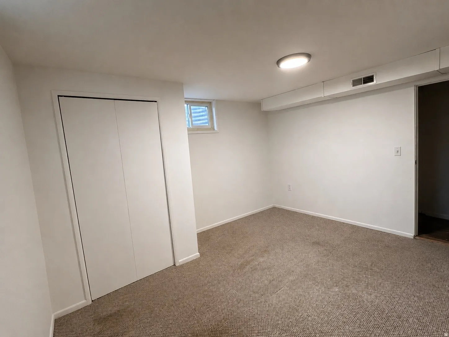 Interior room featuring light-colored carpet flooring, white painted walls, and a ceiling-mounted flush light fixture
