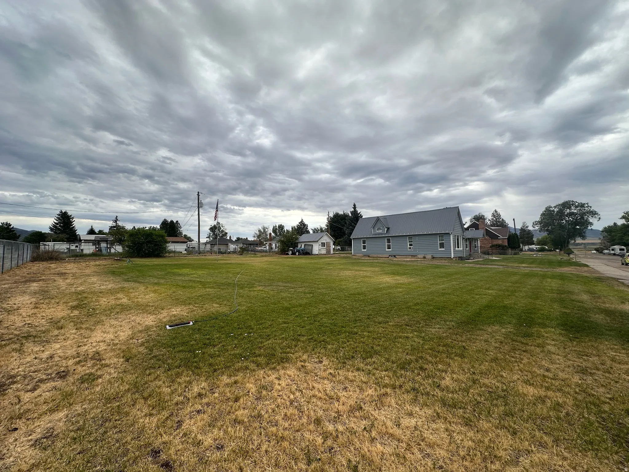 Expansive grassy lot with a partially fenced perimeter