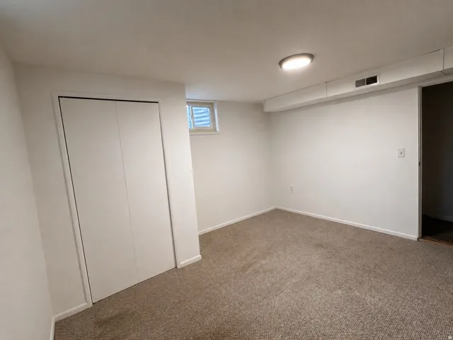 Interior room featuring light-colored carpet flooring, white painted walls, and a ceiling-mounted flush light fixture