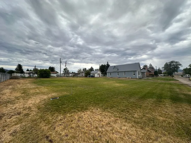 Expansive grassy lot with a partially fenced perimeter