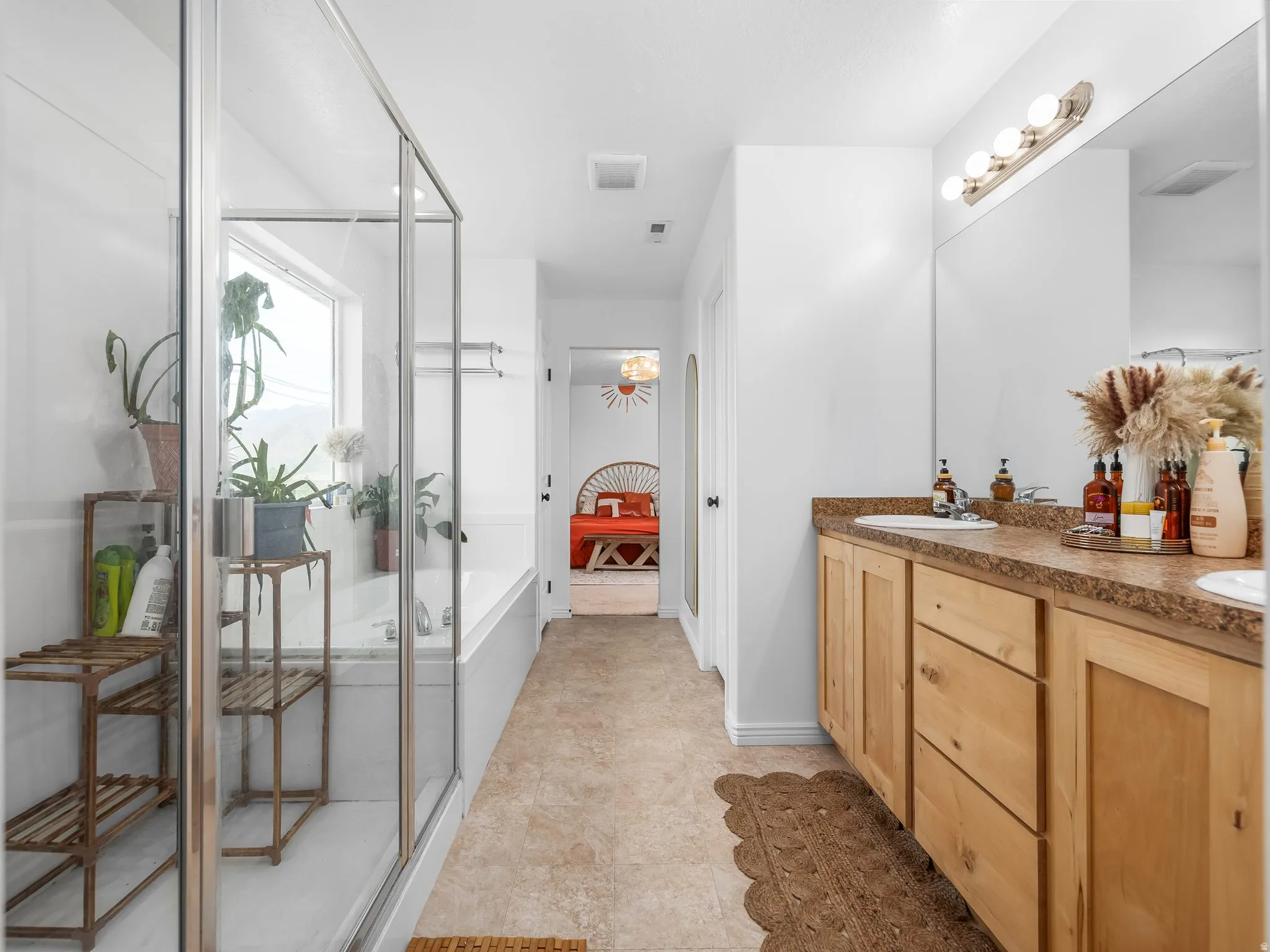Full bath featuring ensuite bath, double vanity, a shower stall, and a garden tub