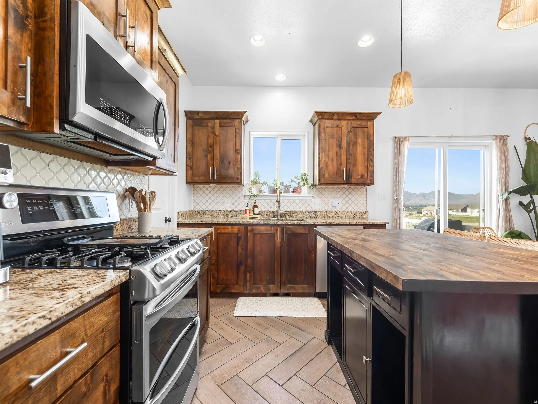 Kitchen featuring wooden counters, stainless steel appliances, decorative light fixtures, parquet floors, and decorative backsplash
